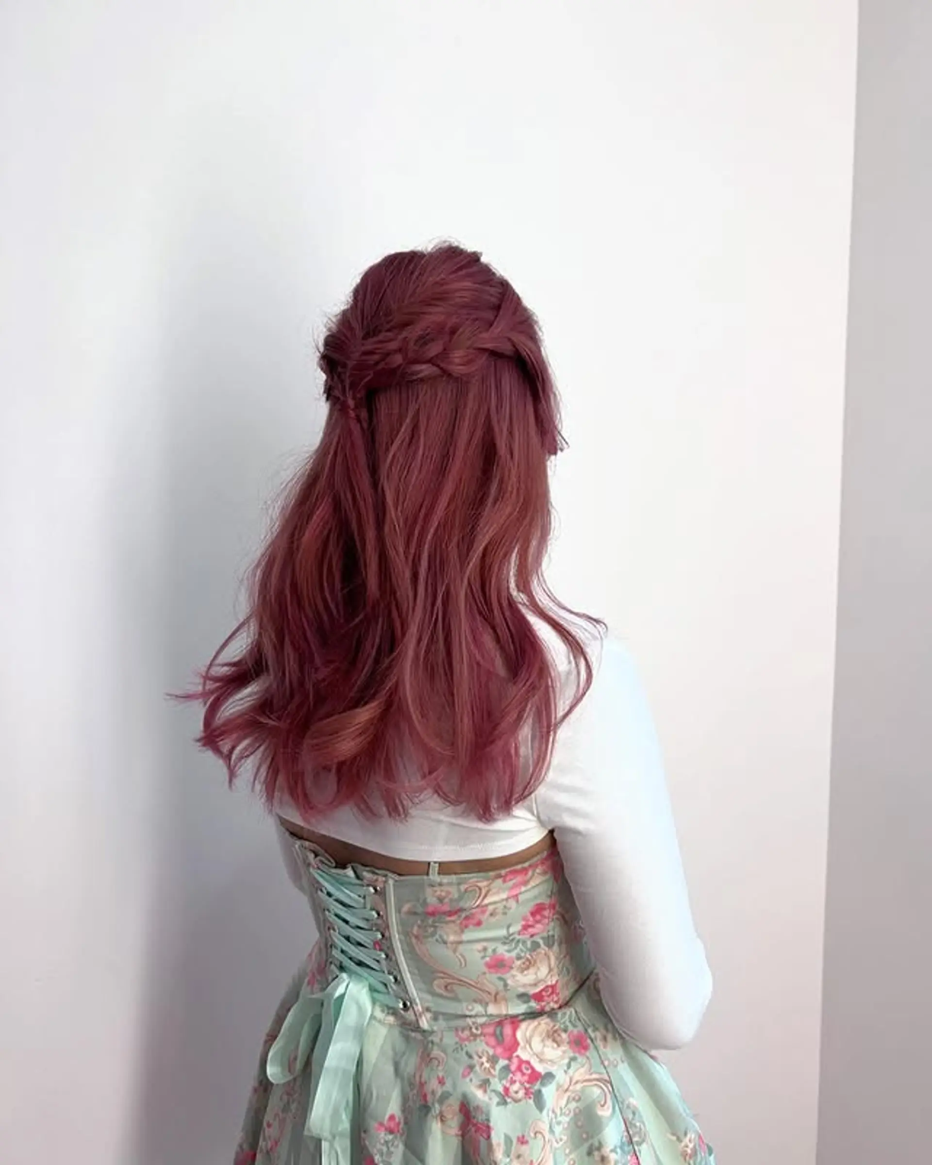A wavy, rose colored hairstyle styled in a half updo with a braided crown. 1