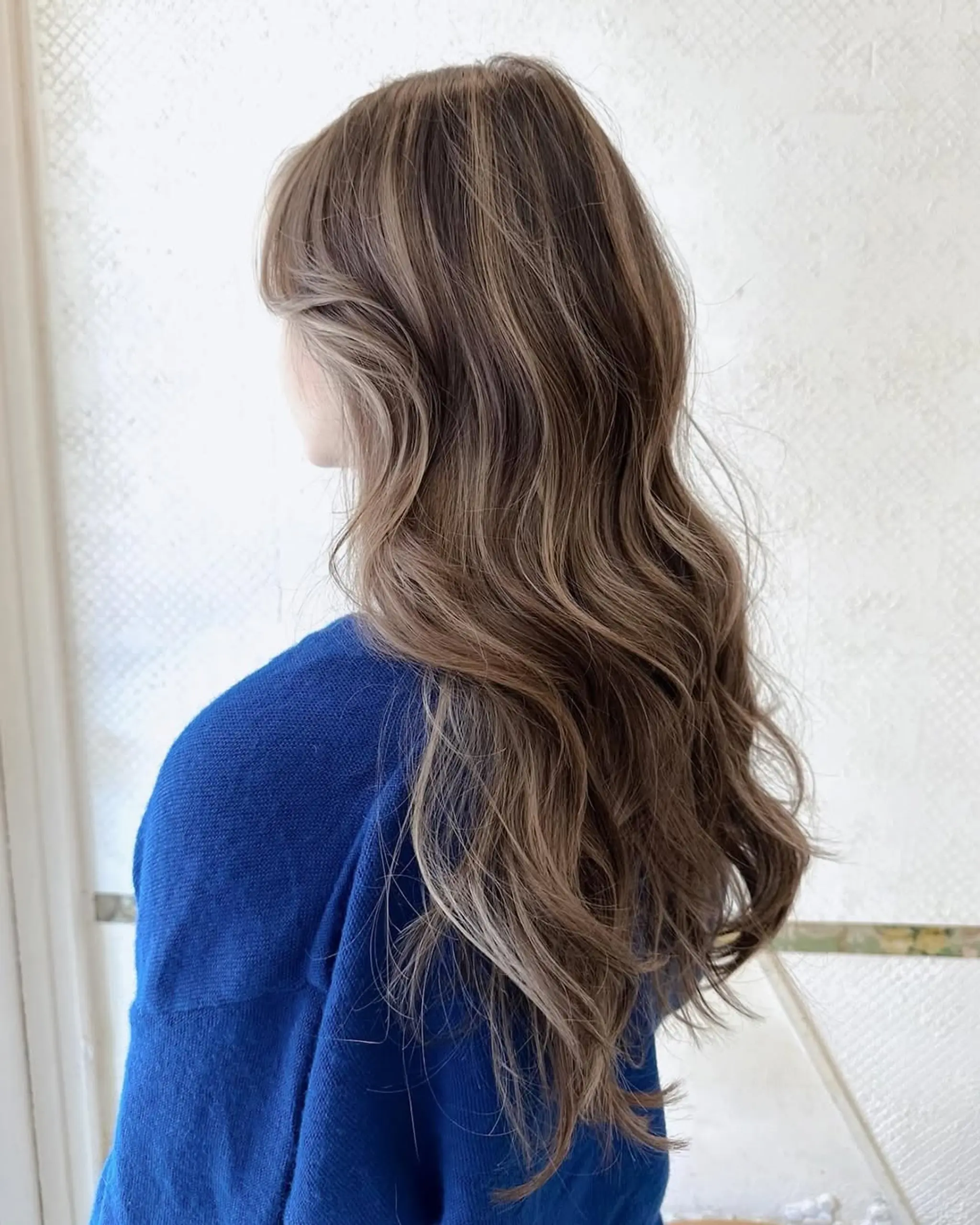 Long, wavy hairstyle with ash brown base and honey blonde highlights, featuring loose waves and soft layers for natural movement. 1
