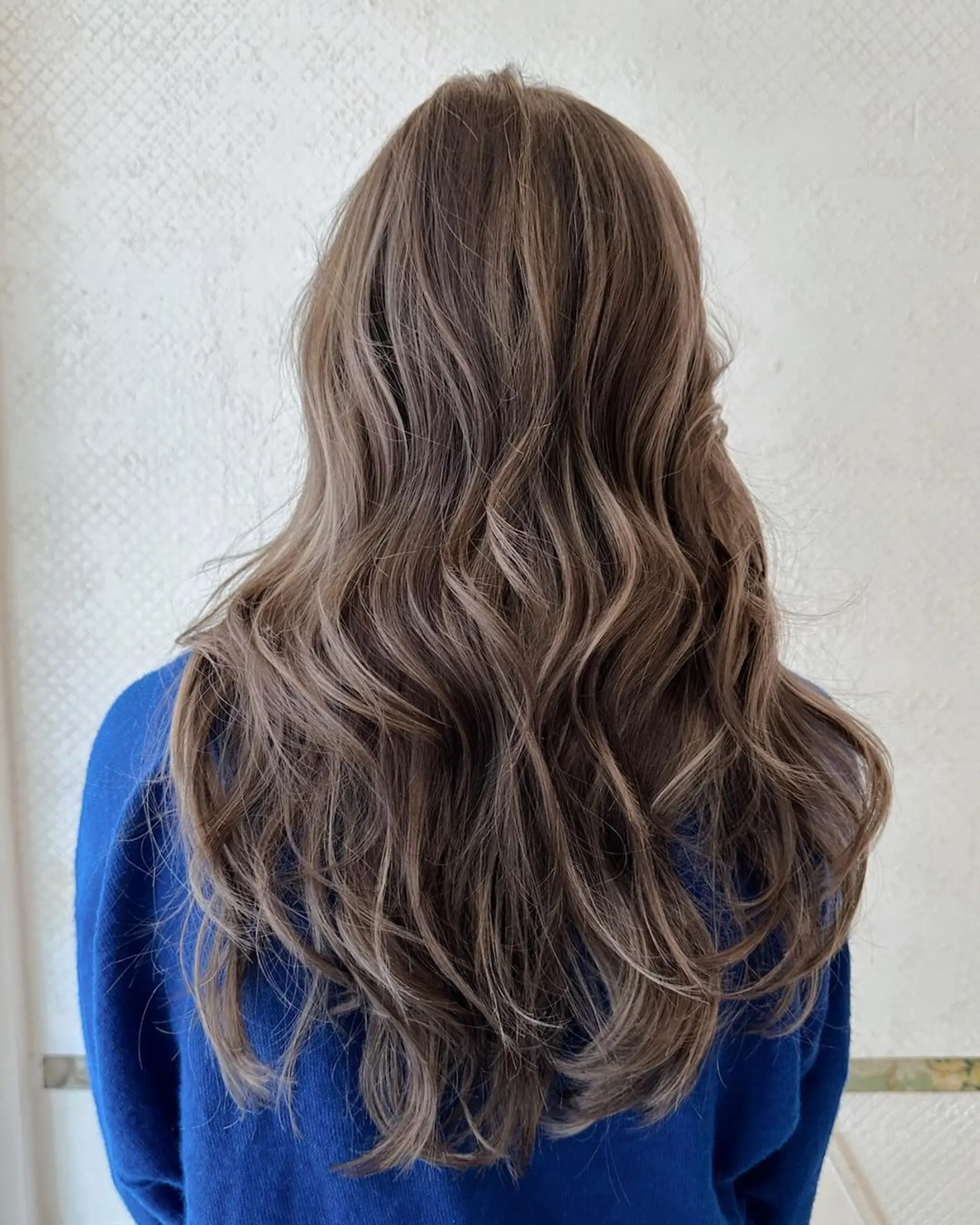 Long, wavy hairstyle with ash brown base and honey blonde highlights, featuring loose waves and soft layers for natural movement. 2