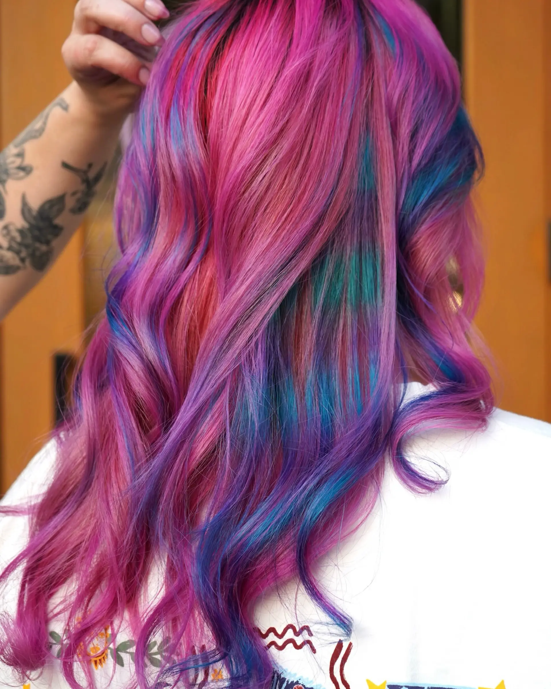 Vibrant long wavy hair featuring a cotton candy blend of bright pink, purple, blue, and teal shades. 1