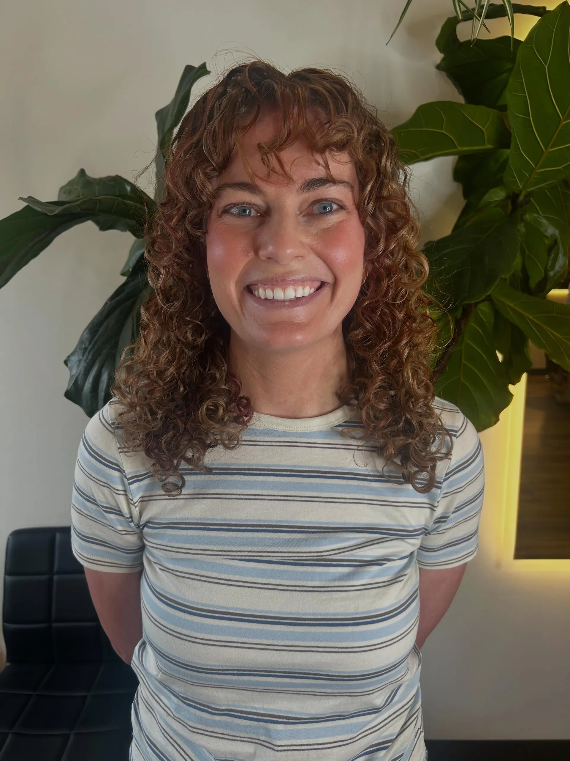 Medium-length layered curly haircut featuring defined ringlets and face-framing curly bangs. 1