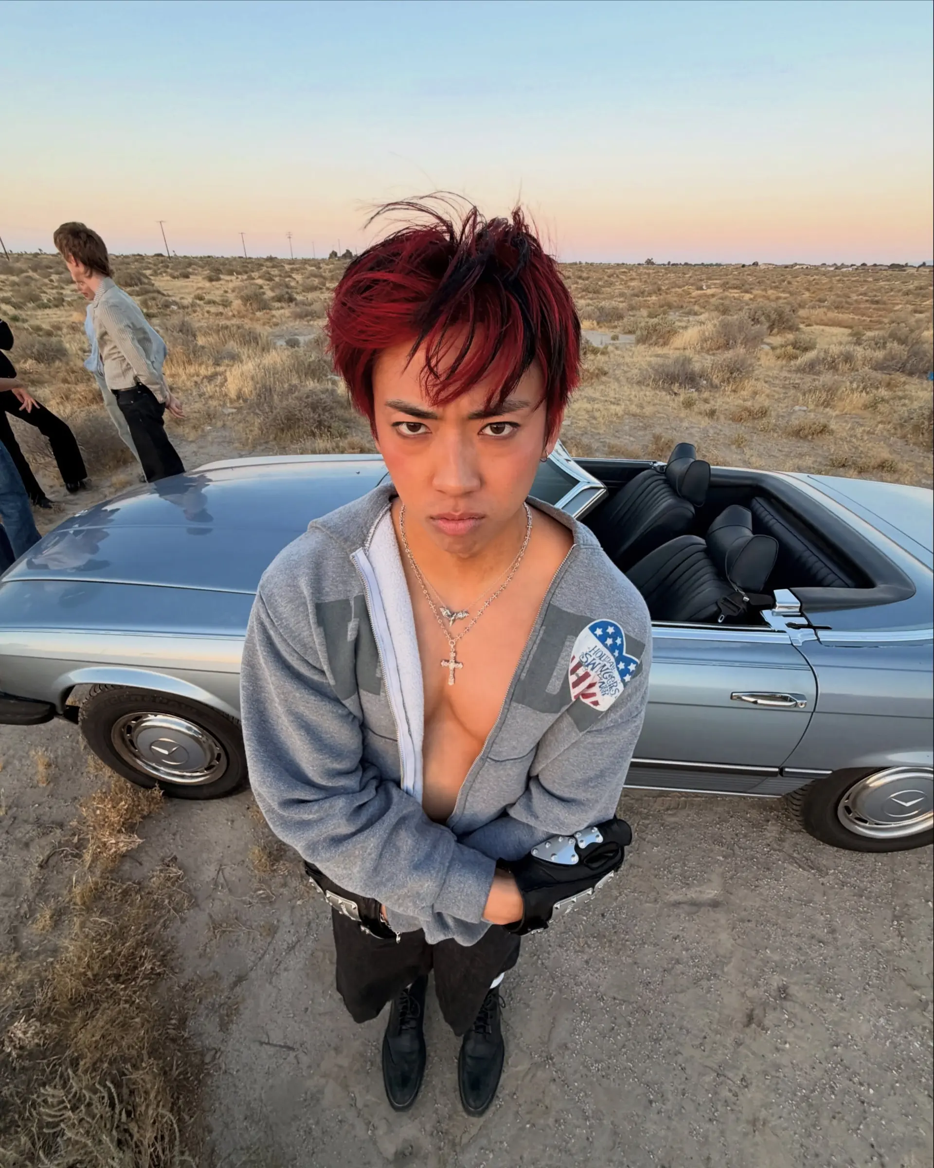 A bold short haircut featuring vibrant crimson red coloring with contrasting dark strands, styled forward into a textured, piecey fringe. 1