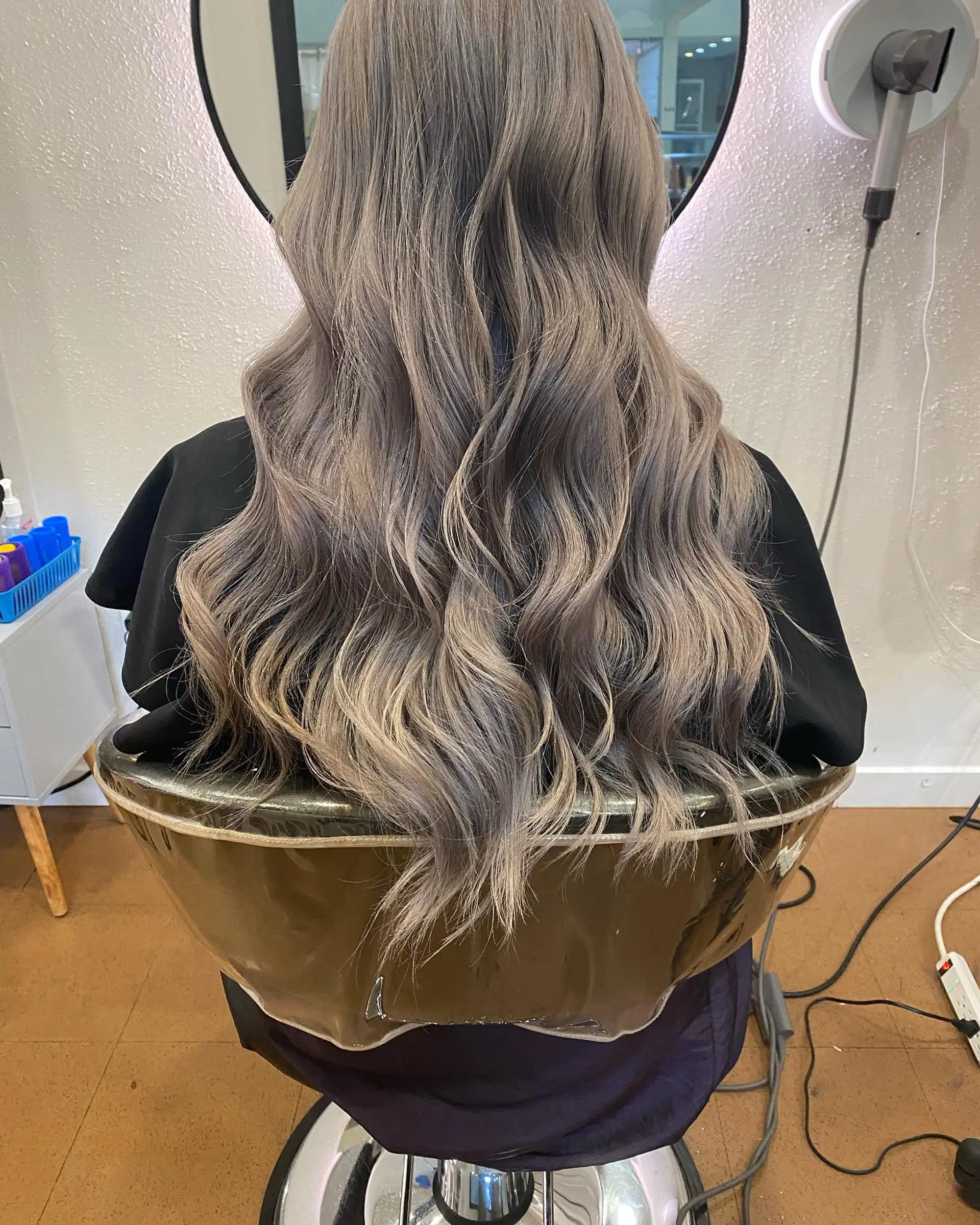Long ash beige balayage styled in soft, loose waves cascading down the back. 1