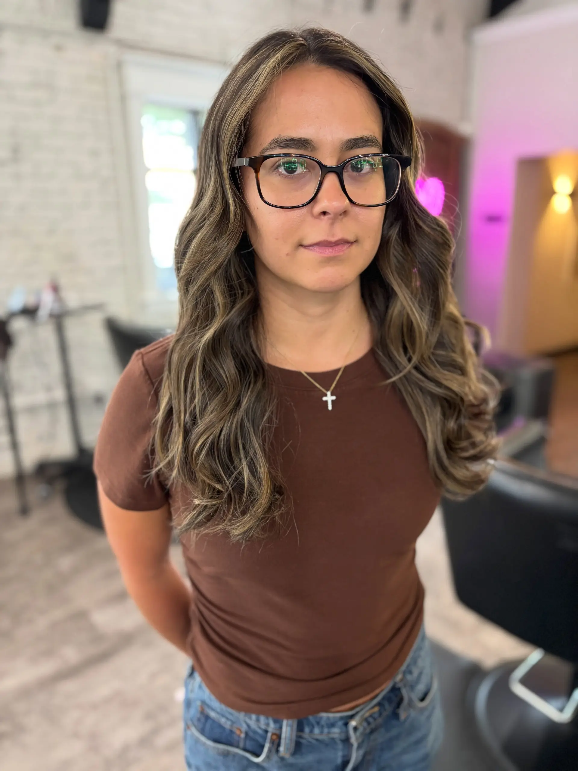 Long wavy dark hair enhanced with dimensional caramel and subtle blonde highlights, styled in soft, loose waves. 1