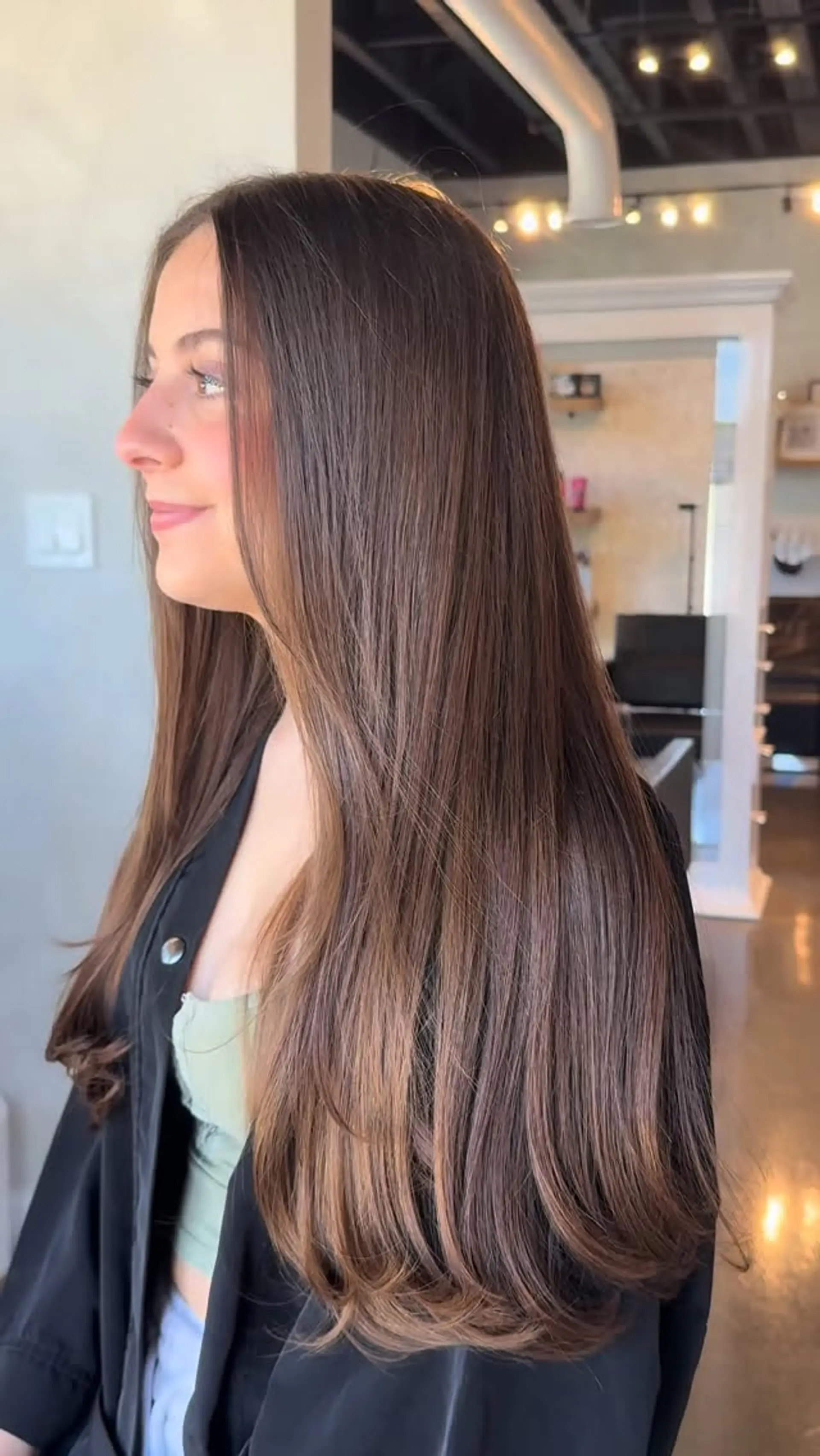 Long, silky brunette hair styled straight with gentle inward curved ends and subtle face-framing layers. 1