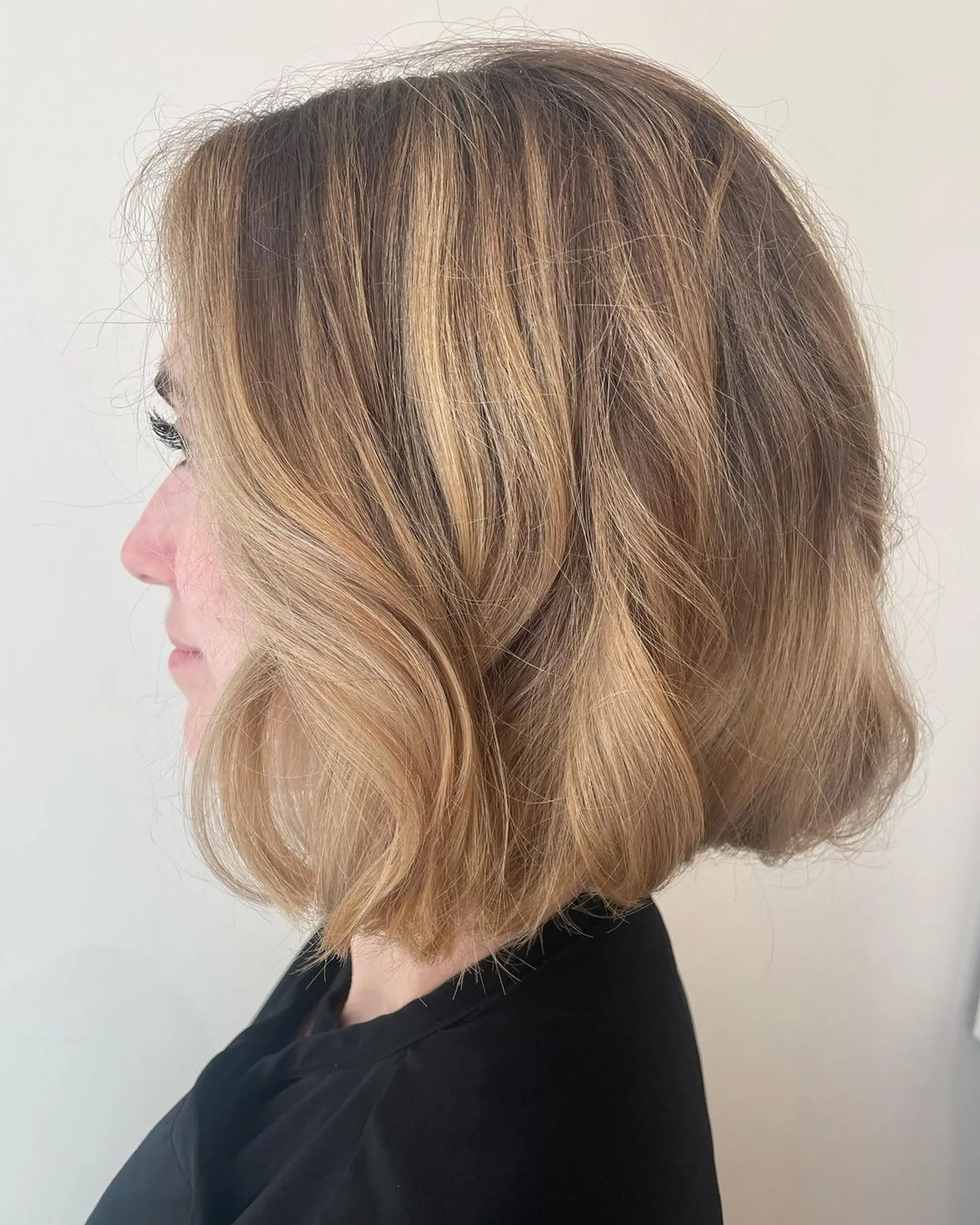 A short, wavy chin-length bob, featuring soft waves and subtle layers with a side part.