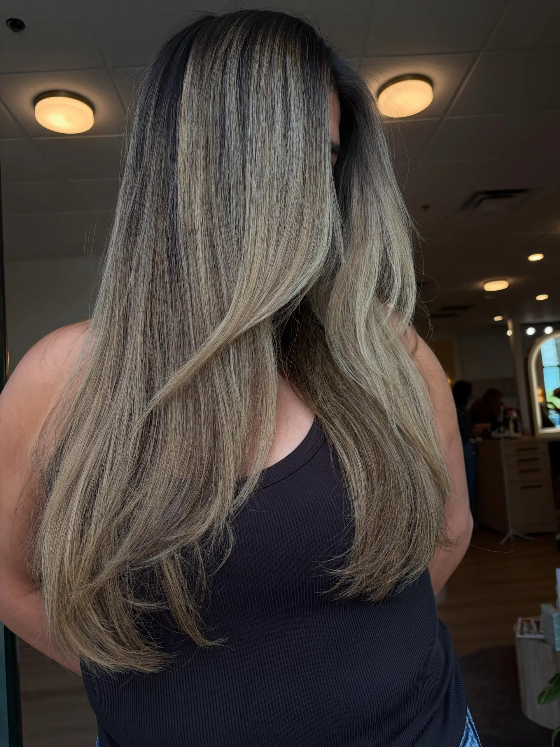 Long, layered hair styled in a smooth blowout featuring seamless, cool-toned ash blonde and bronde dimensional highlights. 1