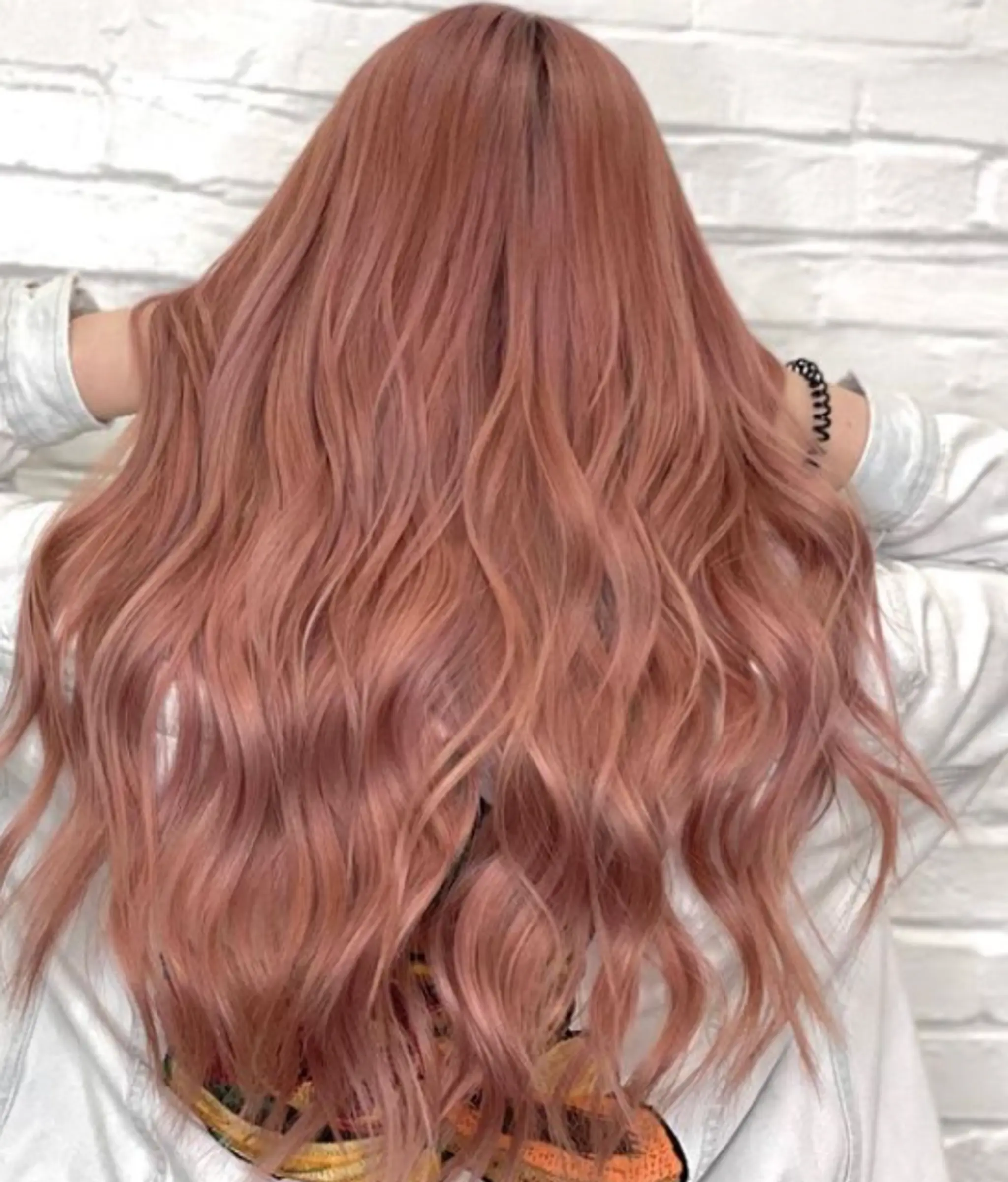 Long, wavy rose gold hair with peach tints, presenting soft waves and voluminous flow.