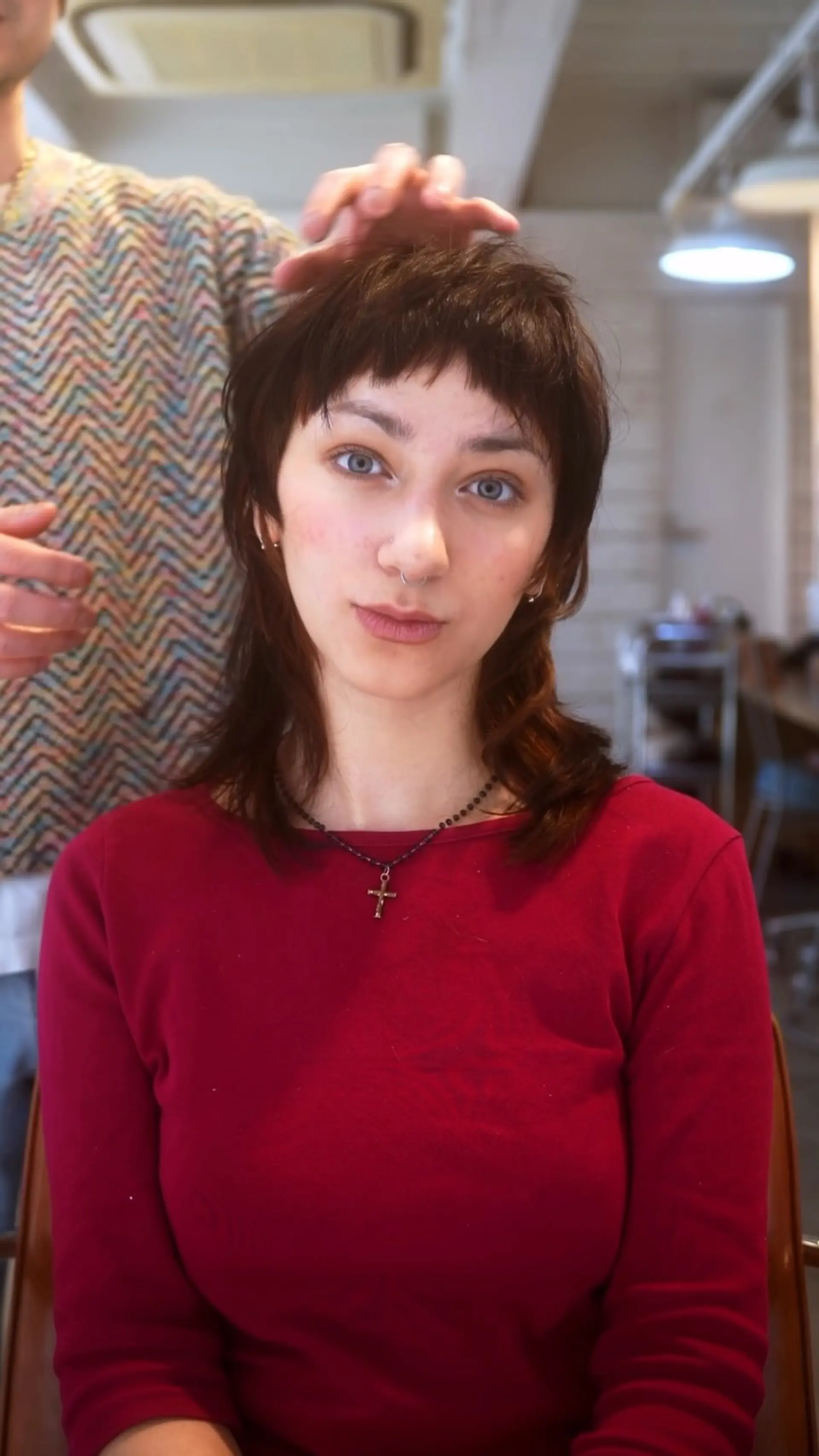 A modern textured shag mullet featuring choppy micro bangs, tapered face-framing layers, and collarbone-skimming ends. 1