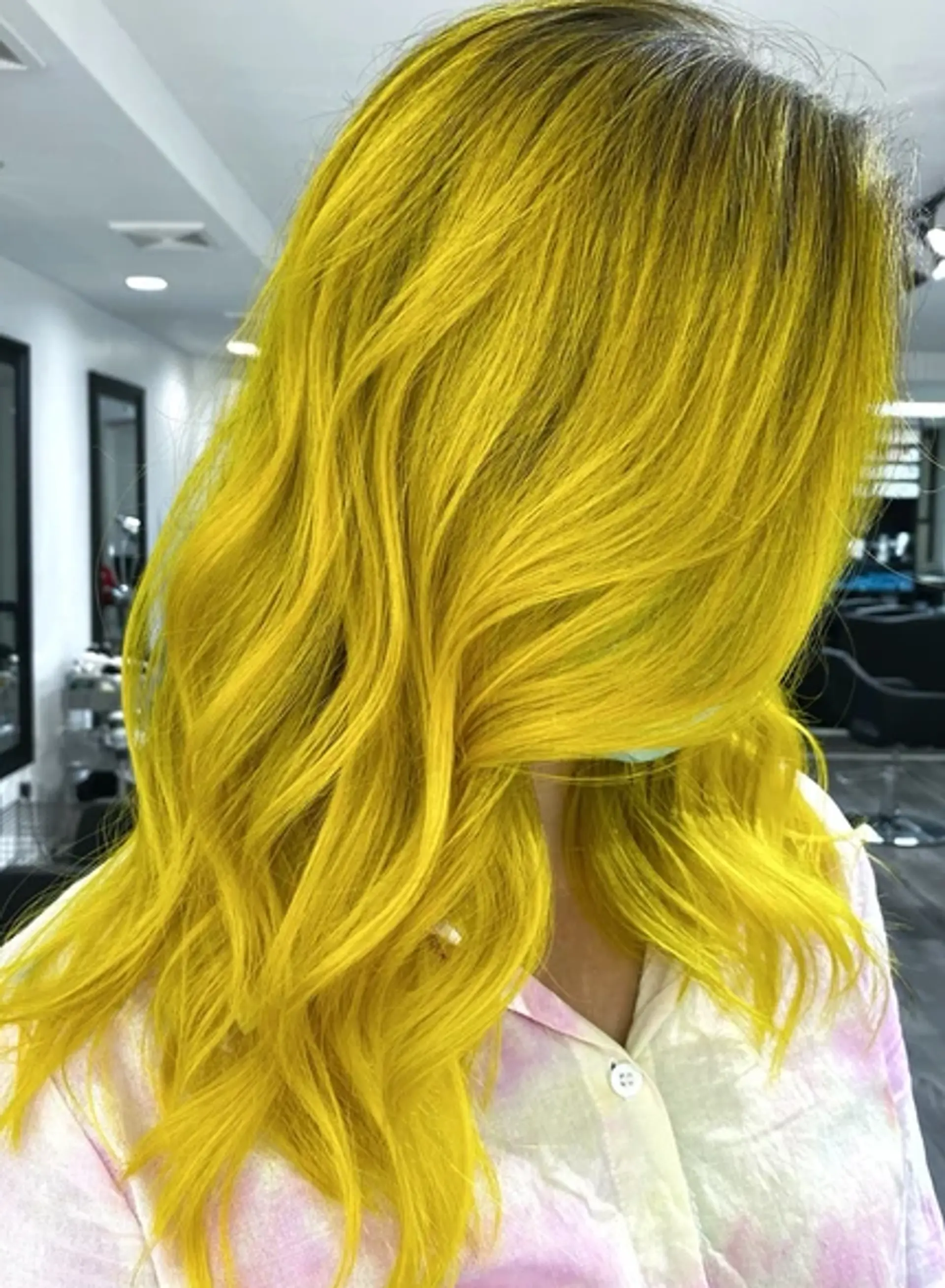 The hairstyle features long, bright yellow waves that cascade gracefully past the shoulders. The hair exhibits a wavy texture, adding volume and movement to the look. The bright yellow color is vibrant and striking, making a bold statement. The waves are soft yet well-defined, giving the hair a dynamic and lively appearance. 1