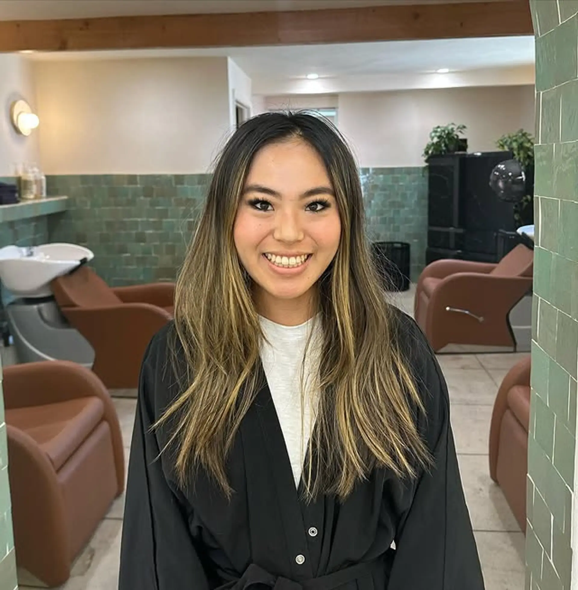 Long, straight hair with dark roots and bronzed blonde balayage, styled in loose beach waves. 1