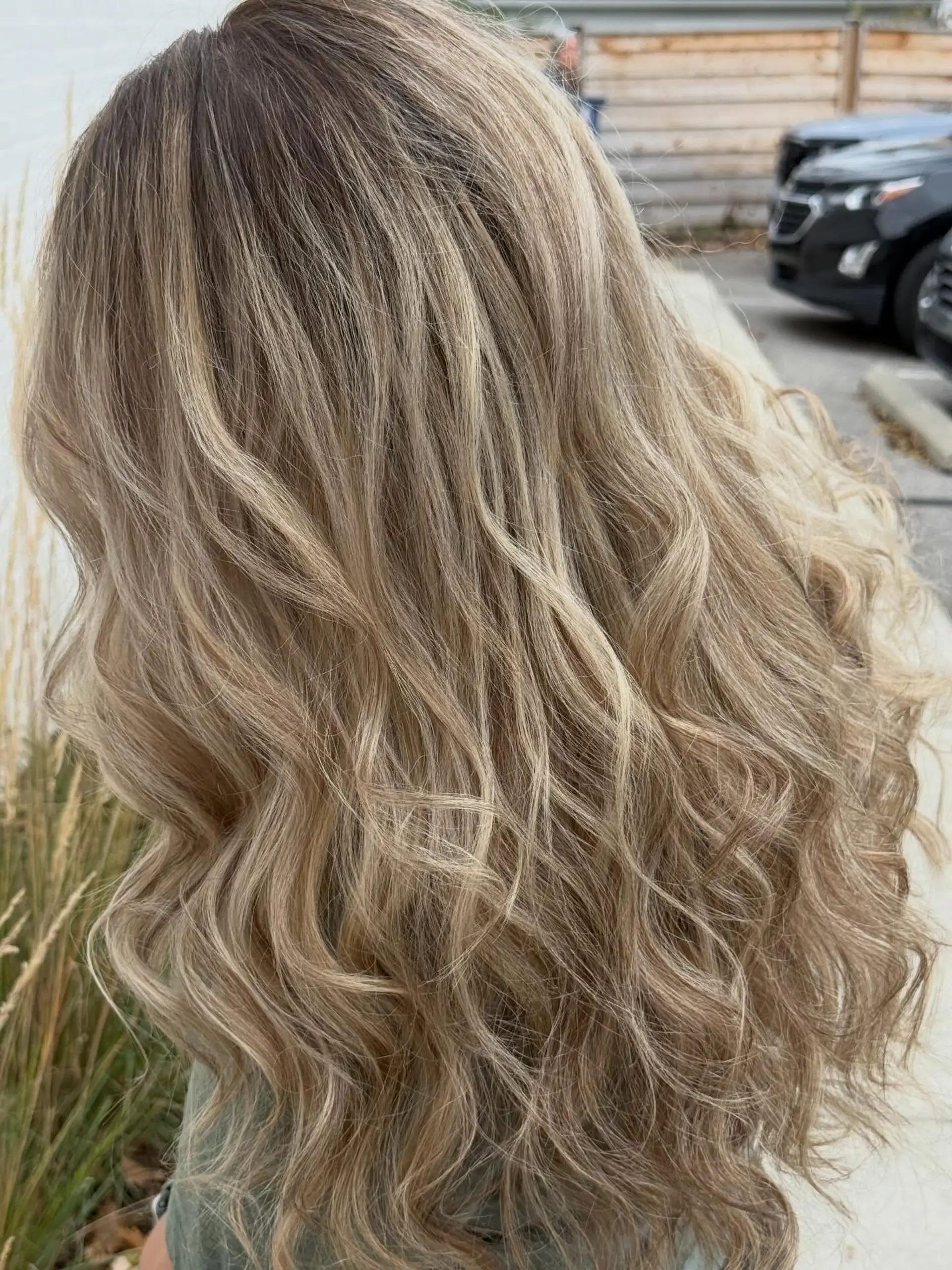 Long, tousled wavy hair showcasing a dimensional beige blonde color blend with soft shadowed lowlights. 1