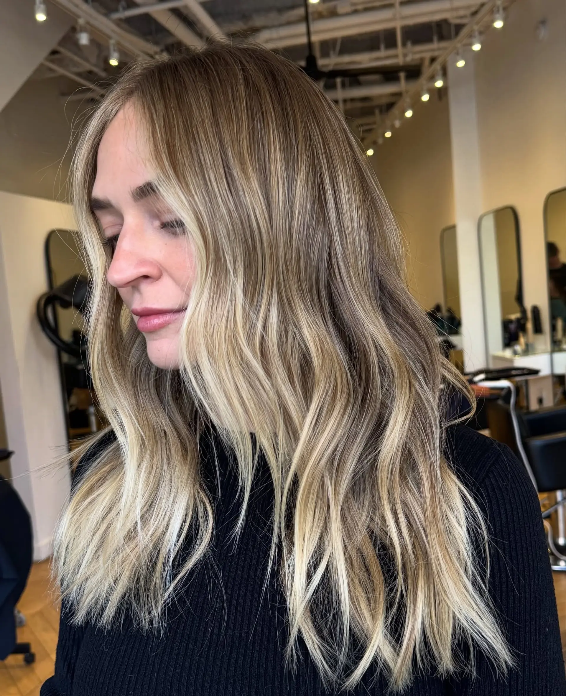 Long wavy hairstyle featuring dimensional blonde highlights and bright face-framing pieces. 1