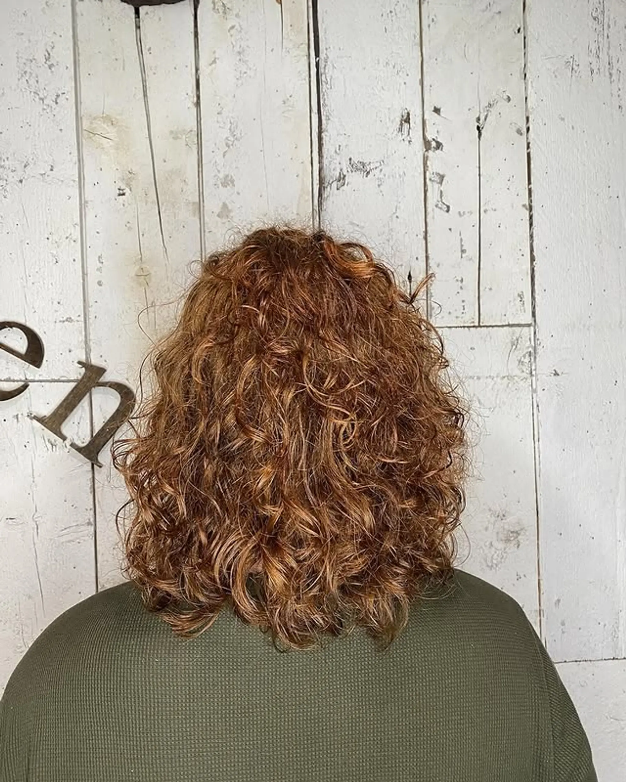 A layered curly bob with copper highlights.