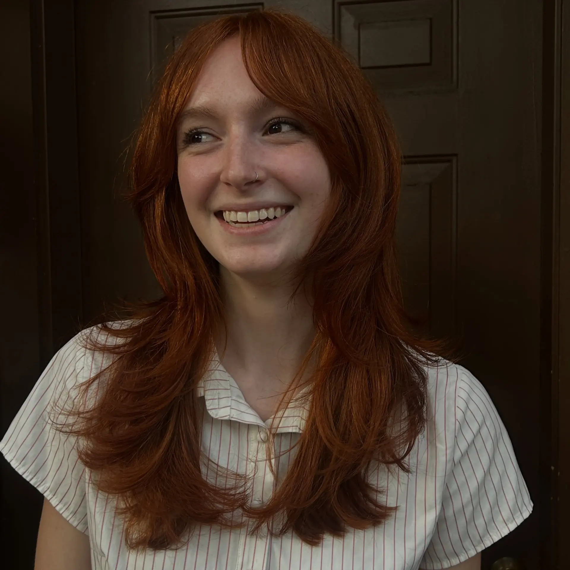 A long, vibrant copper shag haircut styled with wispy bangs and soft, face-framing layers. 1