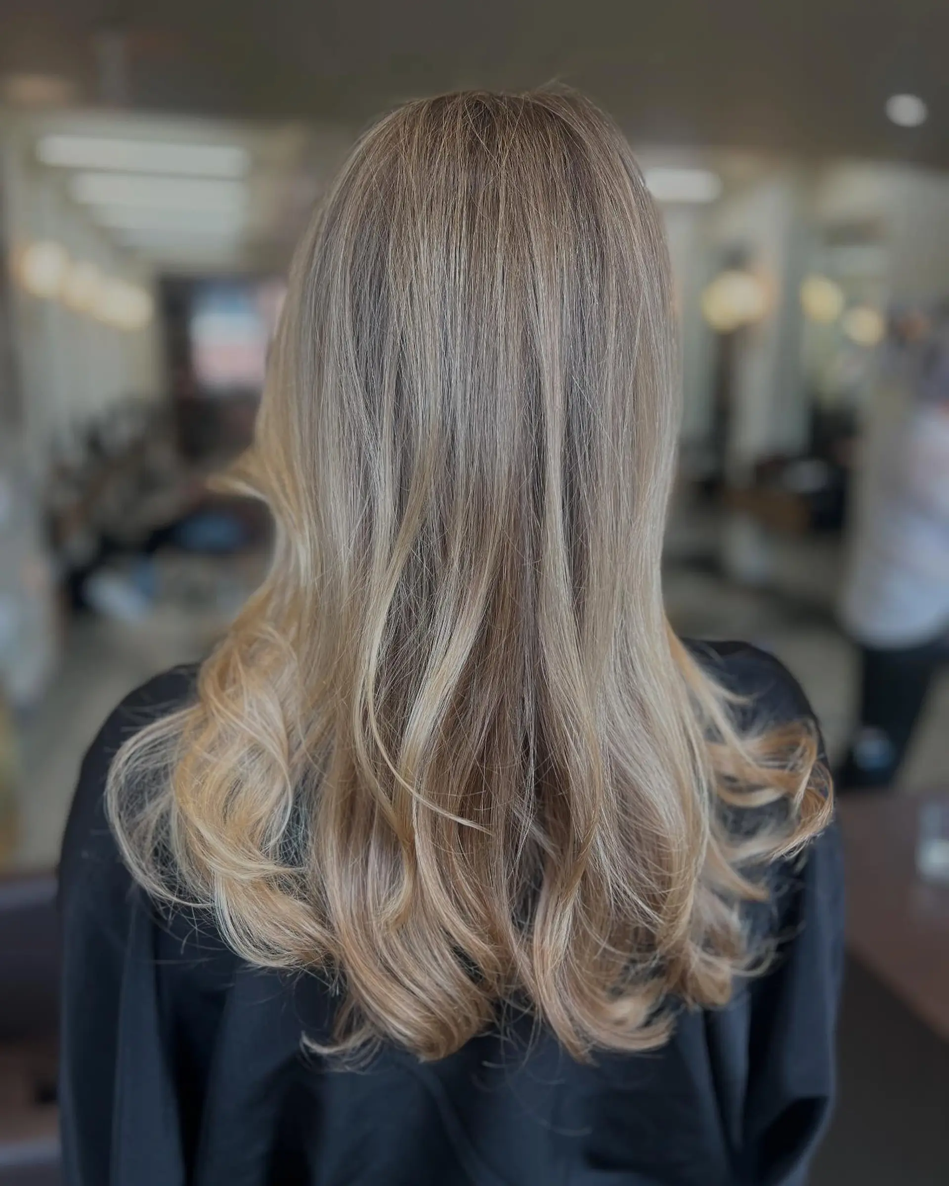 Long golden blonde hair featuring seamless dimensional highlights and soft, bouncy curls at the ends. 1