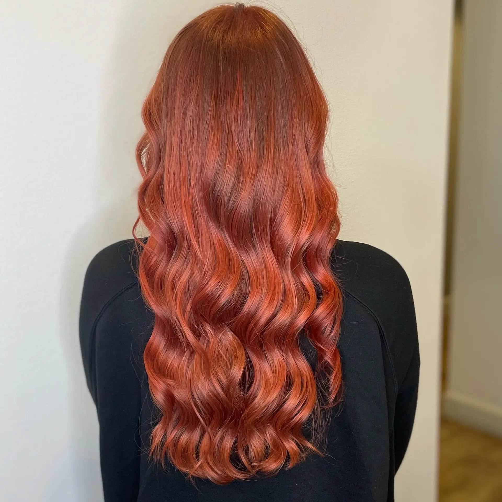 Long vibrant copper-red hair styled into soft, glossy cascading waves. 1