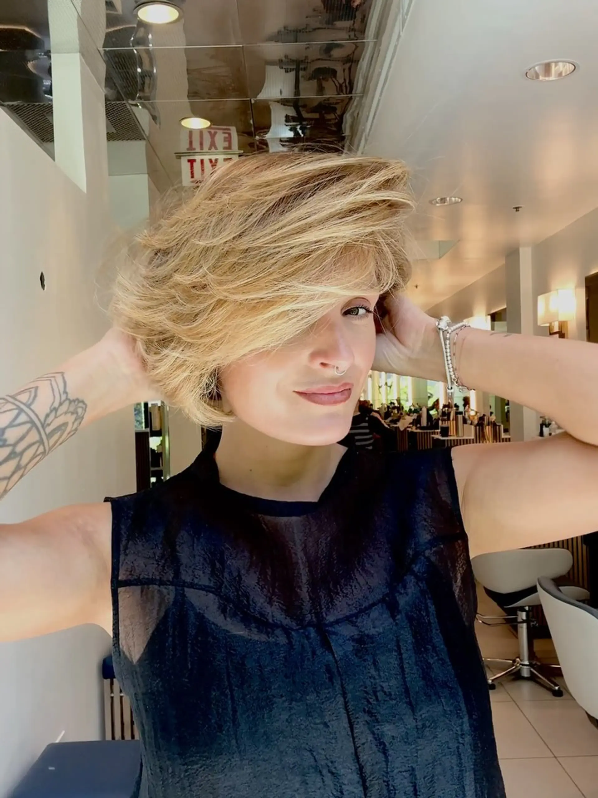 A textured short bob haircut styled with sweeping, voluminous layers and a warm creamy blonde dimensional color. 1