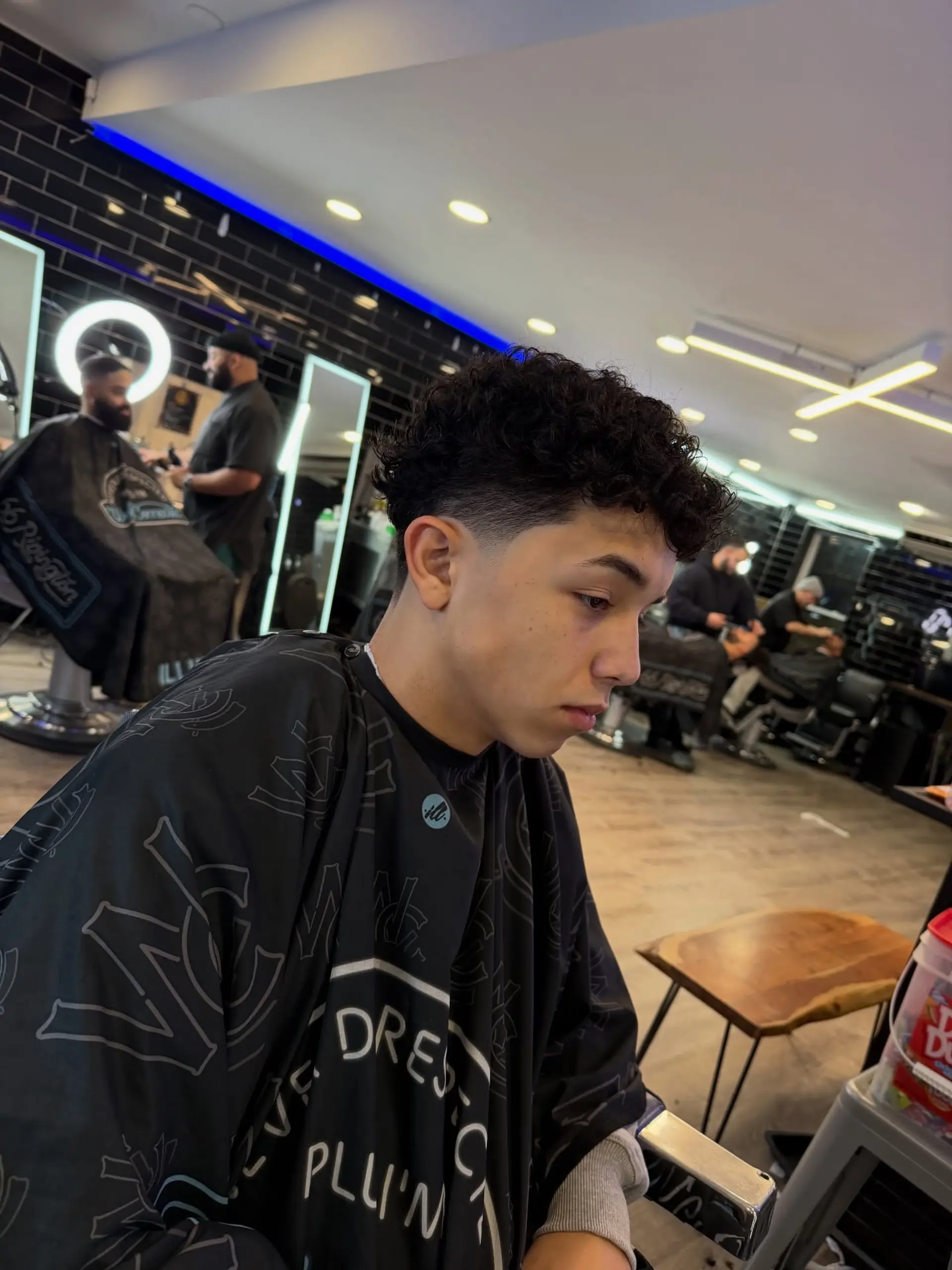 A fresh low taper fade paired with natural textured curls on top and clean edges. 1