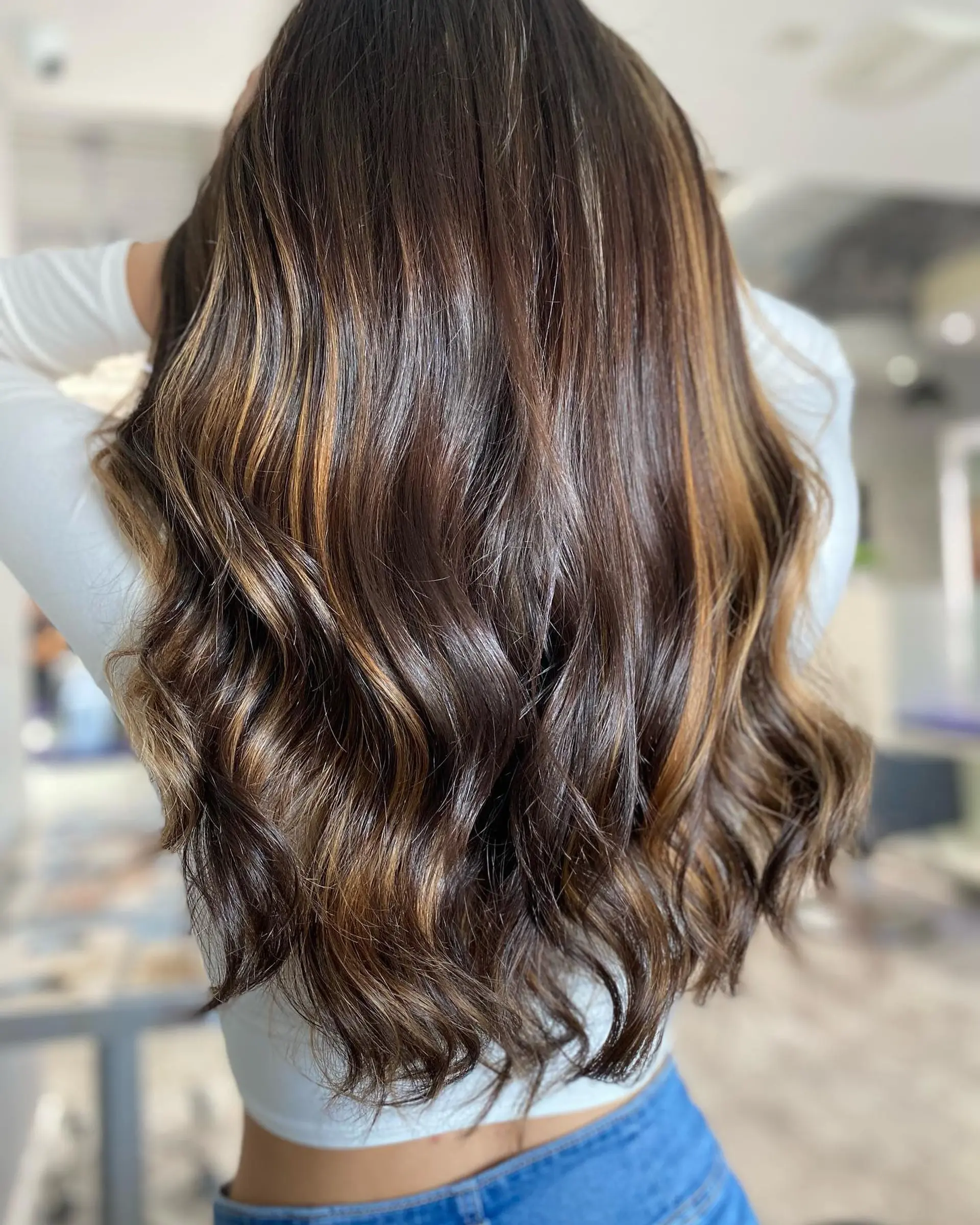 A long wavy hairstyle with face-framing blonde highlights and trendy curtain bangs. 2