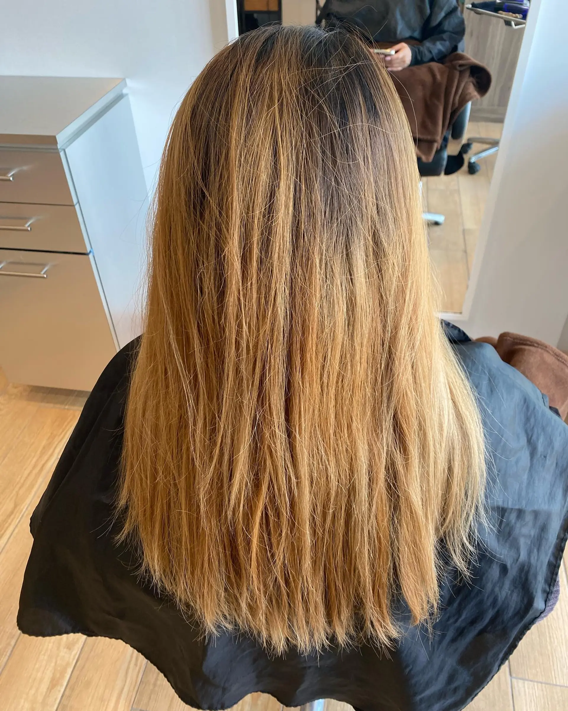 Long straight hair featuring dark natural roots that melt into a warm golden and honey blonde balayage. 1