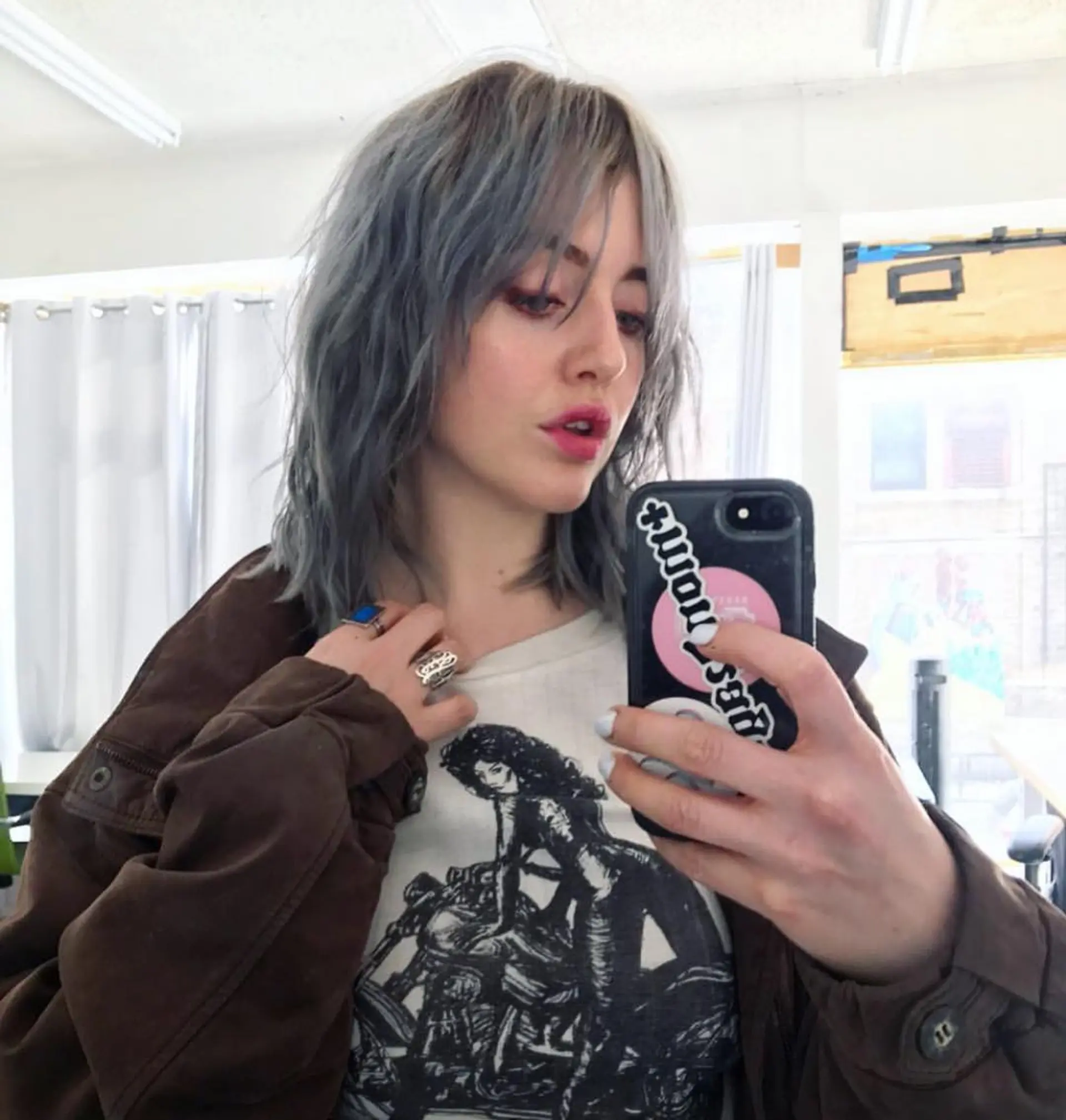 Medium-length wavy hairstyle with gray and silver hues, featuring textured layers, choppy ends, messy waves, and side-swept bangs. 1