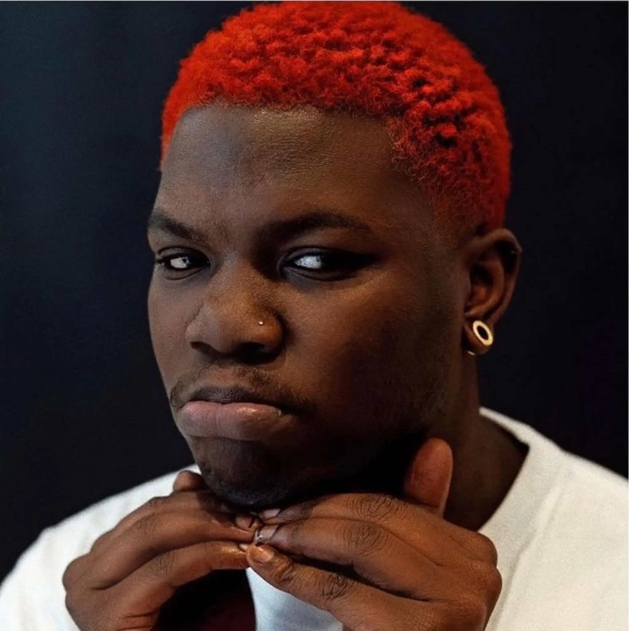 Short, curly hair dyed red with a distinct fade on the sides and back, cut evenly and closely to the scalp. 1