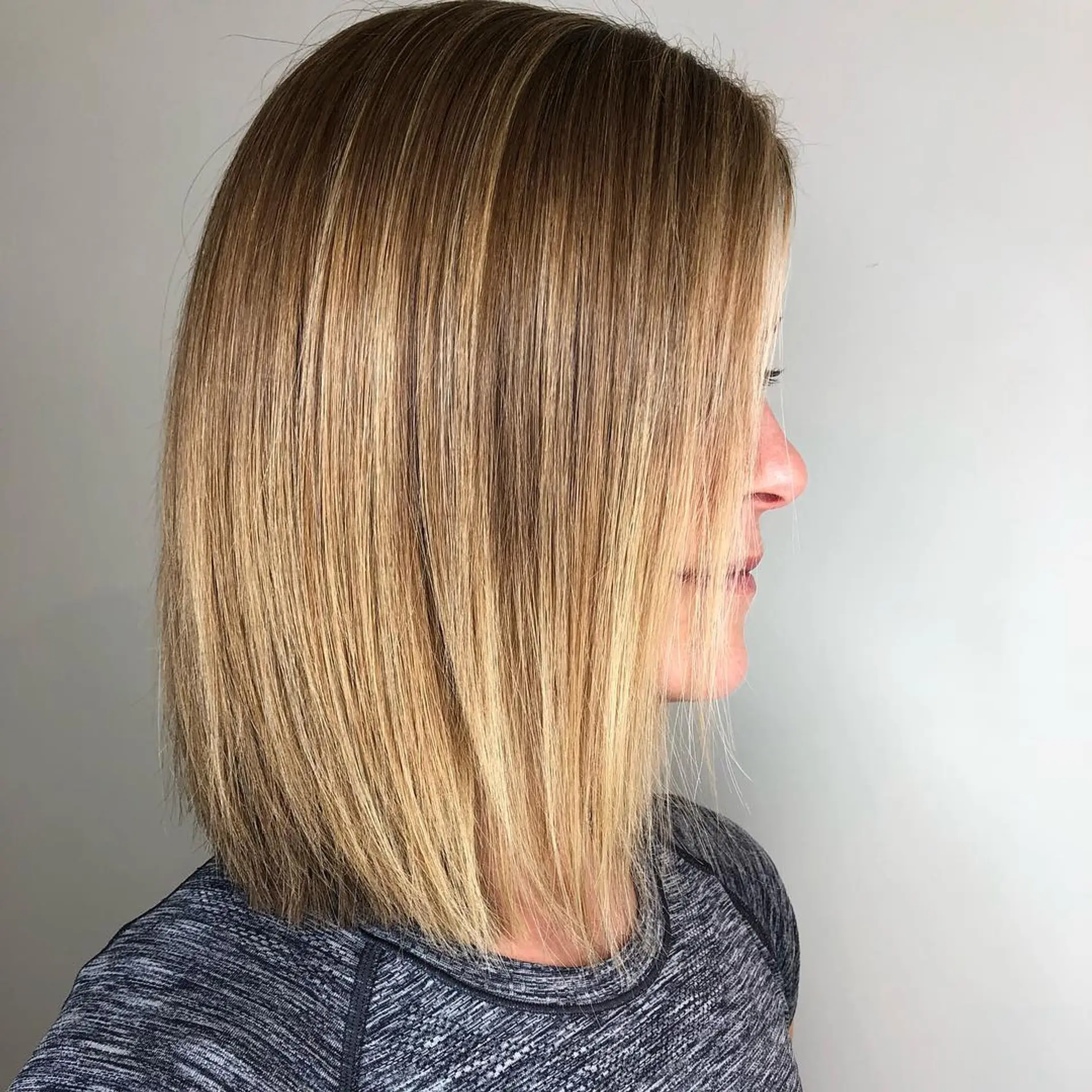 A sleek, straight medium-length blunt lob featuring seamlessly blended blonde highlights. 1