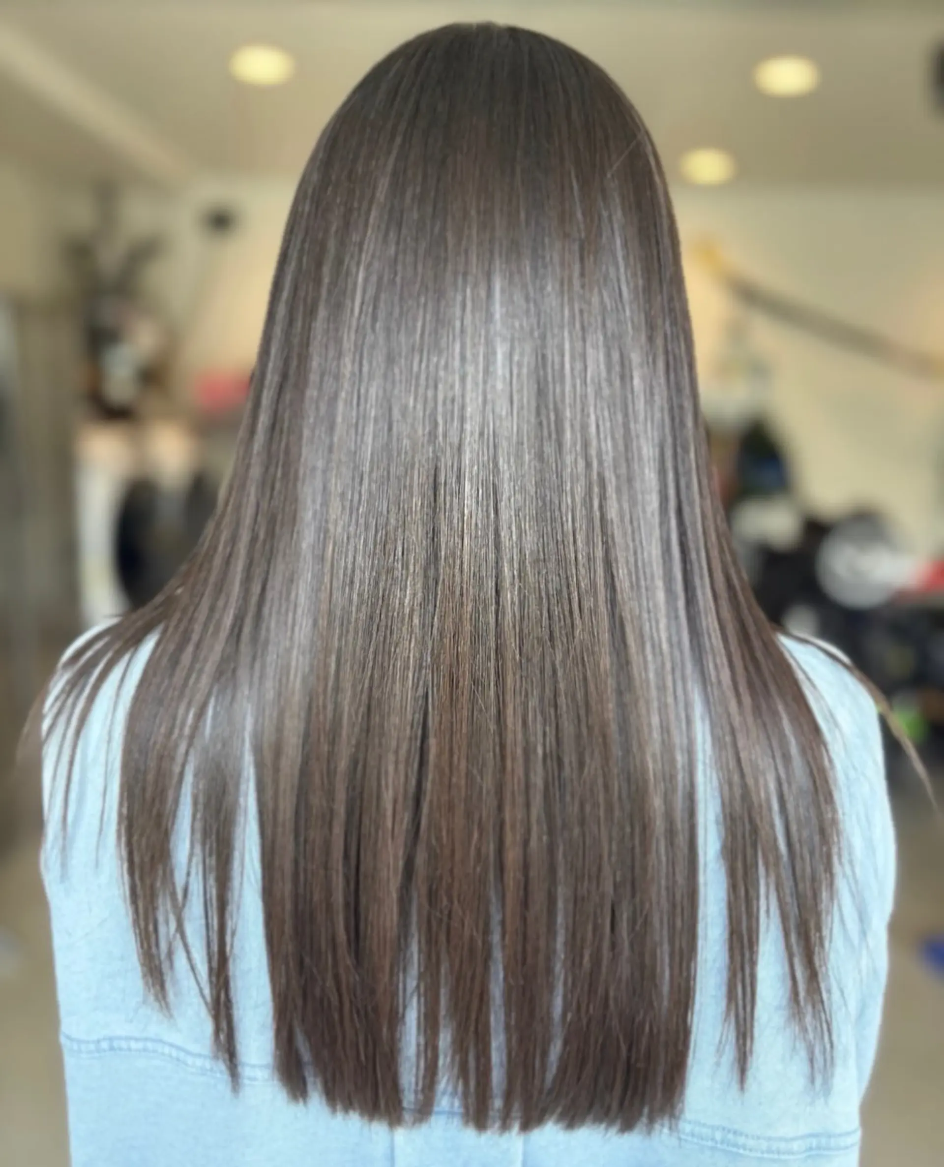 Long, glossy brunette hair styled straight and sleek with a smooth finish. 1
