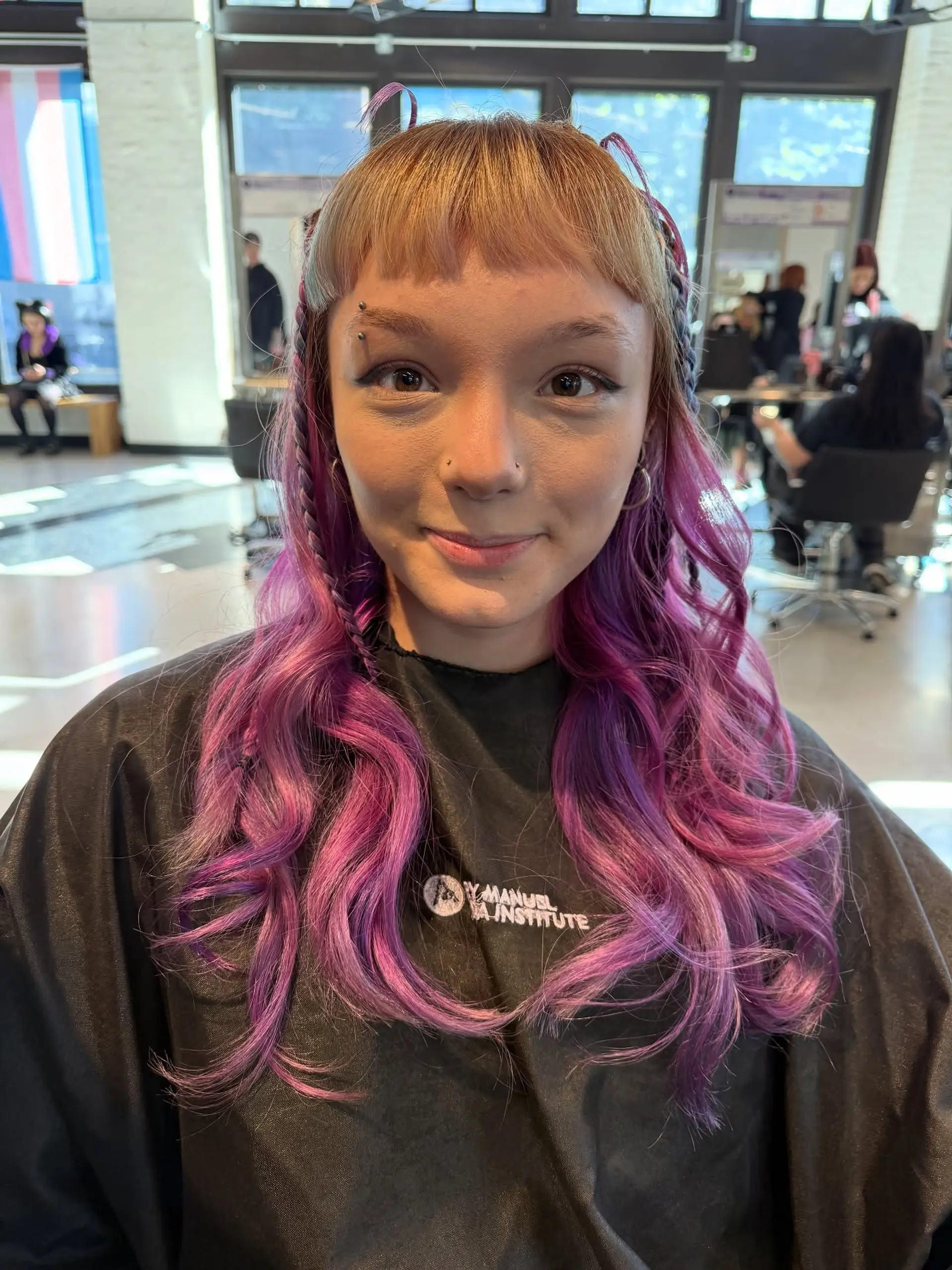 Medium-length wavy purple hair styled with textured curls, blunt micro fringe, and side accent braids. 1