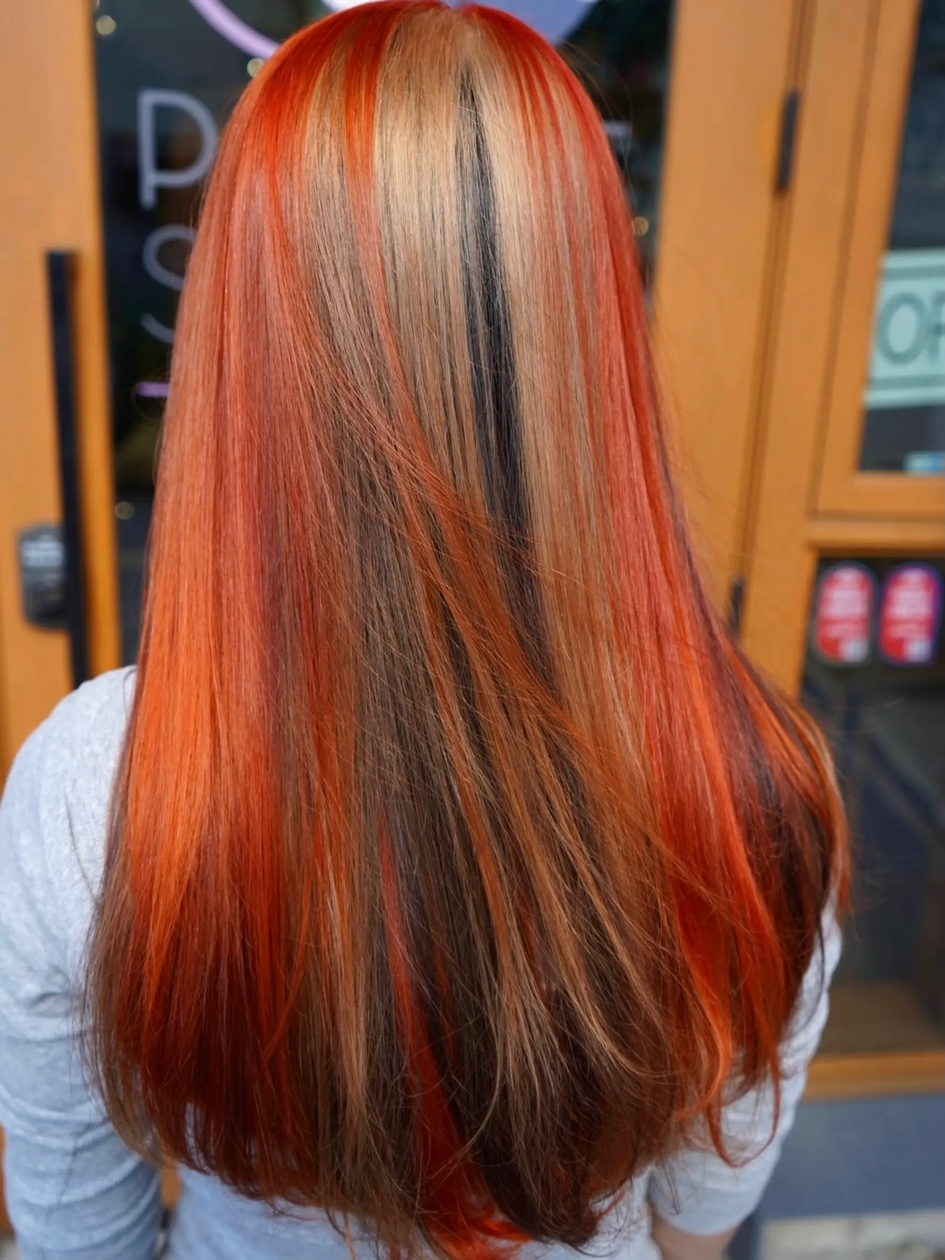 Long straight hair with multi-tonal calico color blocking featuring vivid orange, blonde, and dark brown streaks. 1