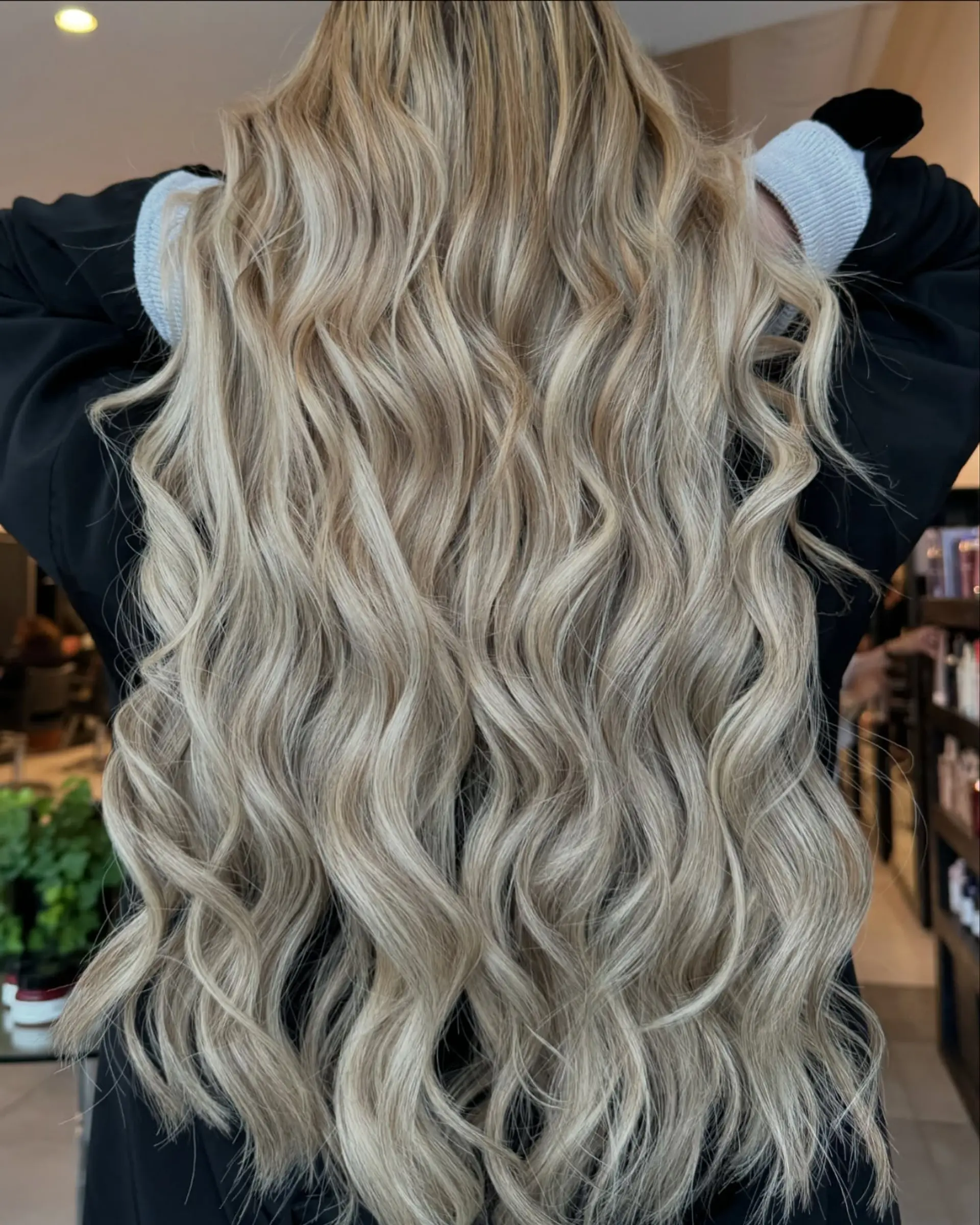 Extra long ash blonde hair styled in flowing, textured loose waves created with weft extensions. 1