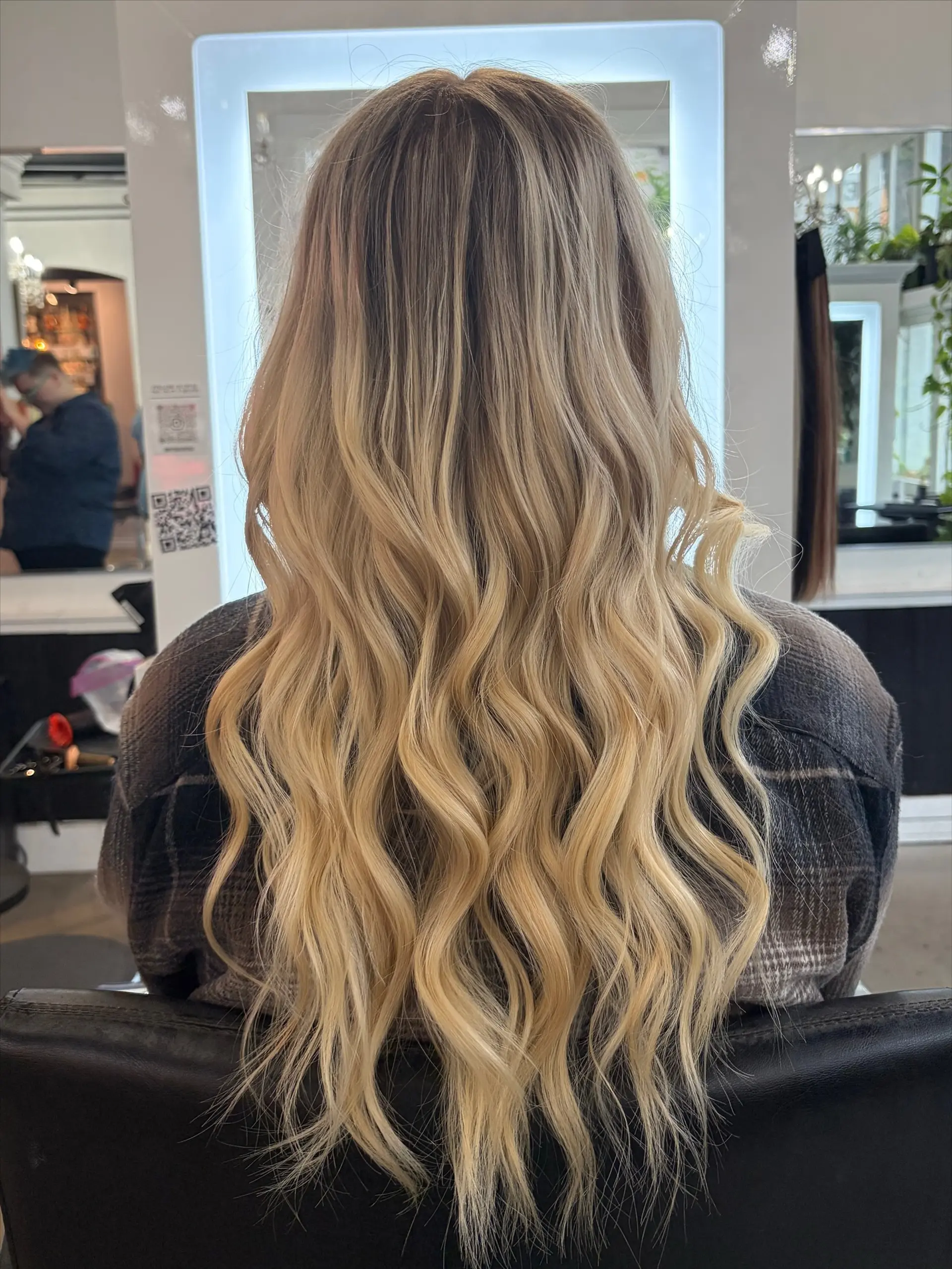 Long cascading blonde hair styled in soft, loose waves with a seamless dimensional root blend. 1