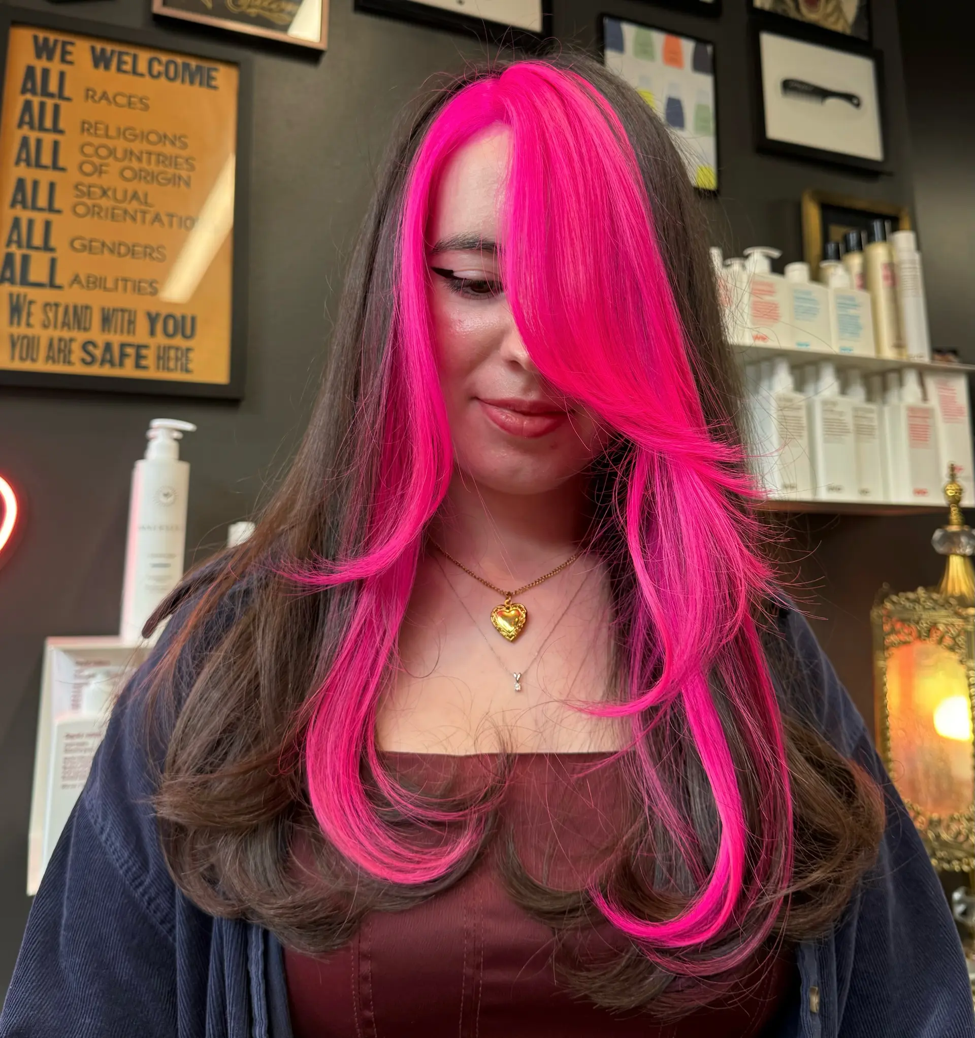 Long dark brown hair featuring a bold neon hot pink face-framing money piece with sweeping layered fringe. 1