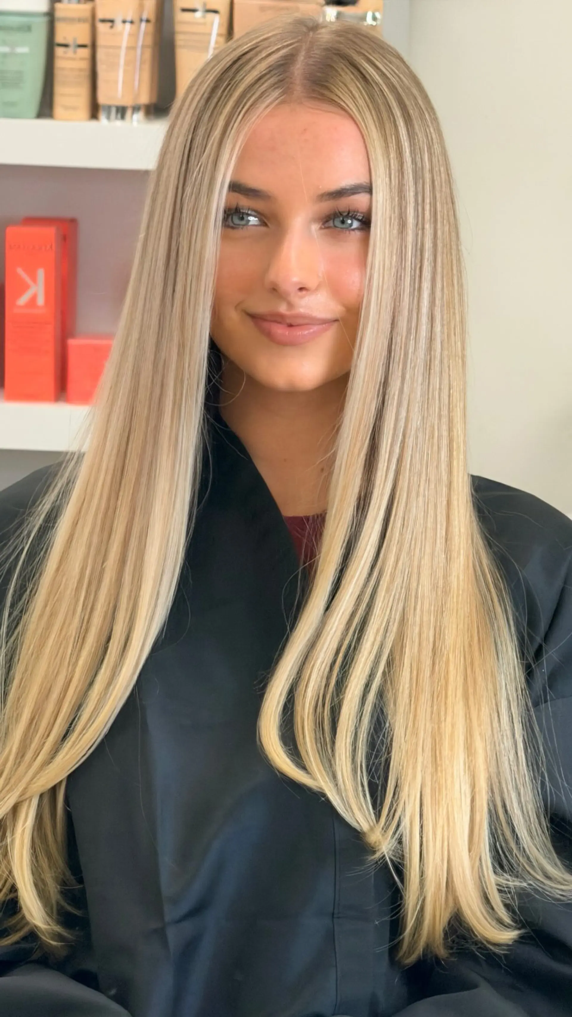 Straight, silky blonde hair parted down the center with subtle dimensional tones and polished ends. 1