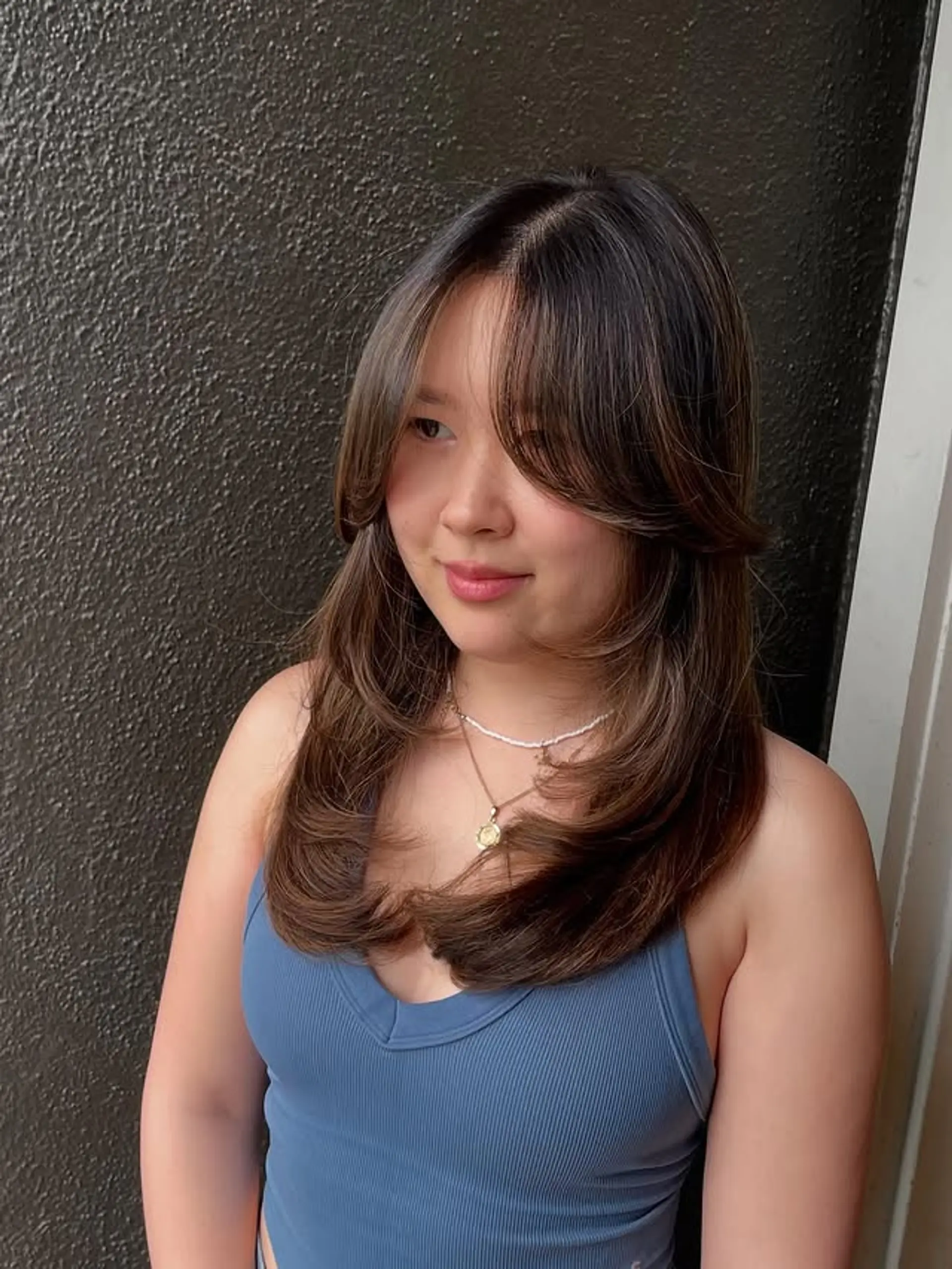 A medium-length layered hairstyle with face-framing layers and curtain bangs. 1