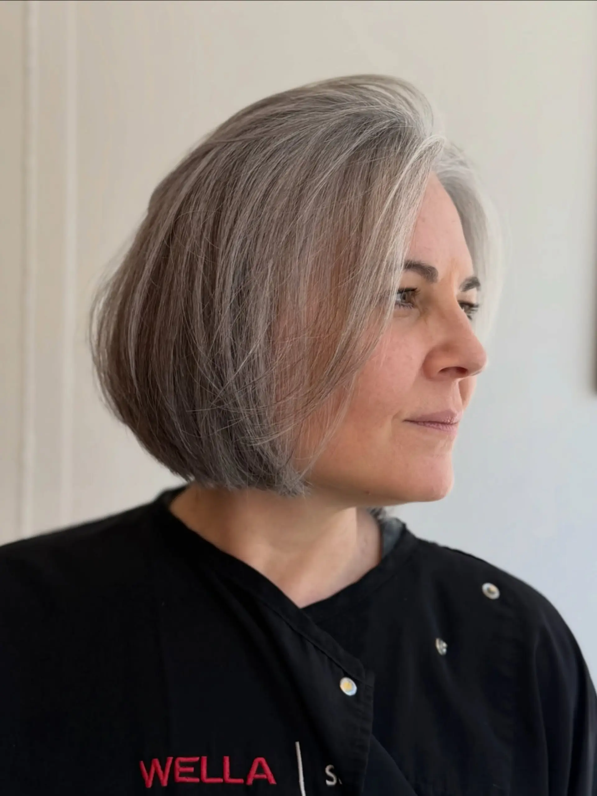 A sleek chin-length modern grey bob styled with gentle volume and inward curve. 1