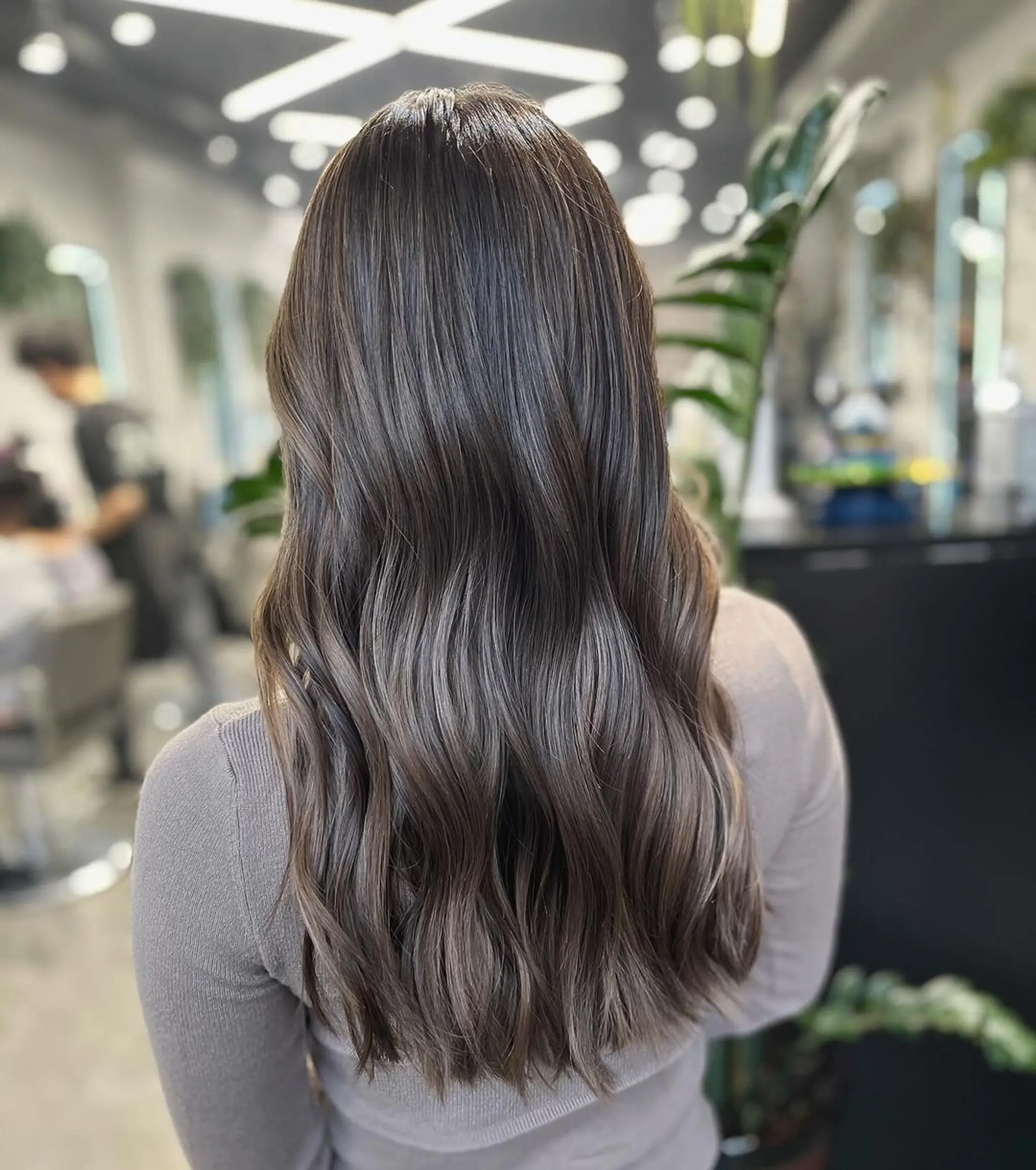 Long, dark brown hair with chestnut highlights styled in loose waves with a center part. The waves have a natural shine and soft layers.
Stylist - @xcellent_jason
