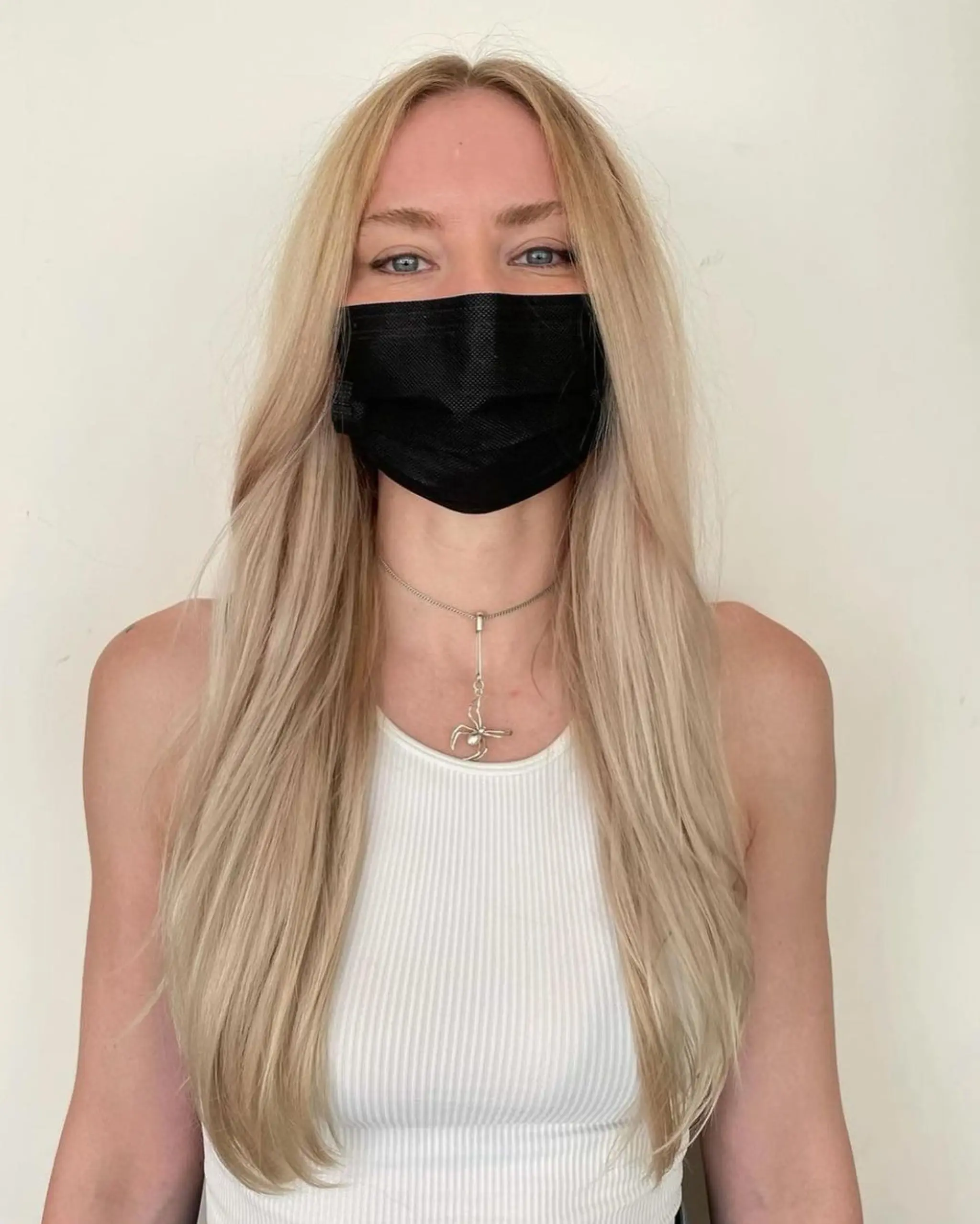 Very long, straight blonde hair with a center part and soft layers, creating a face-framing and naturally shiny style.