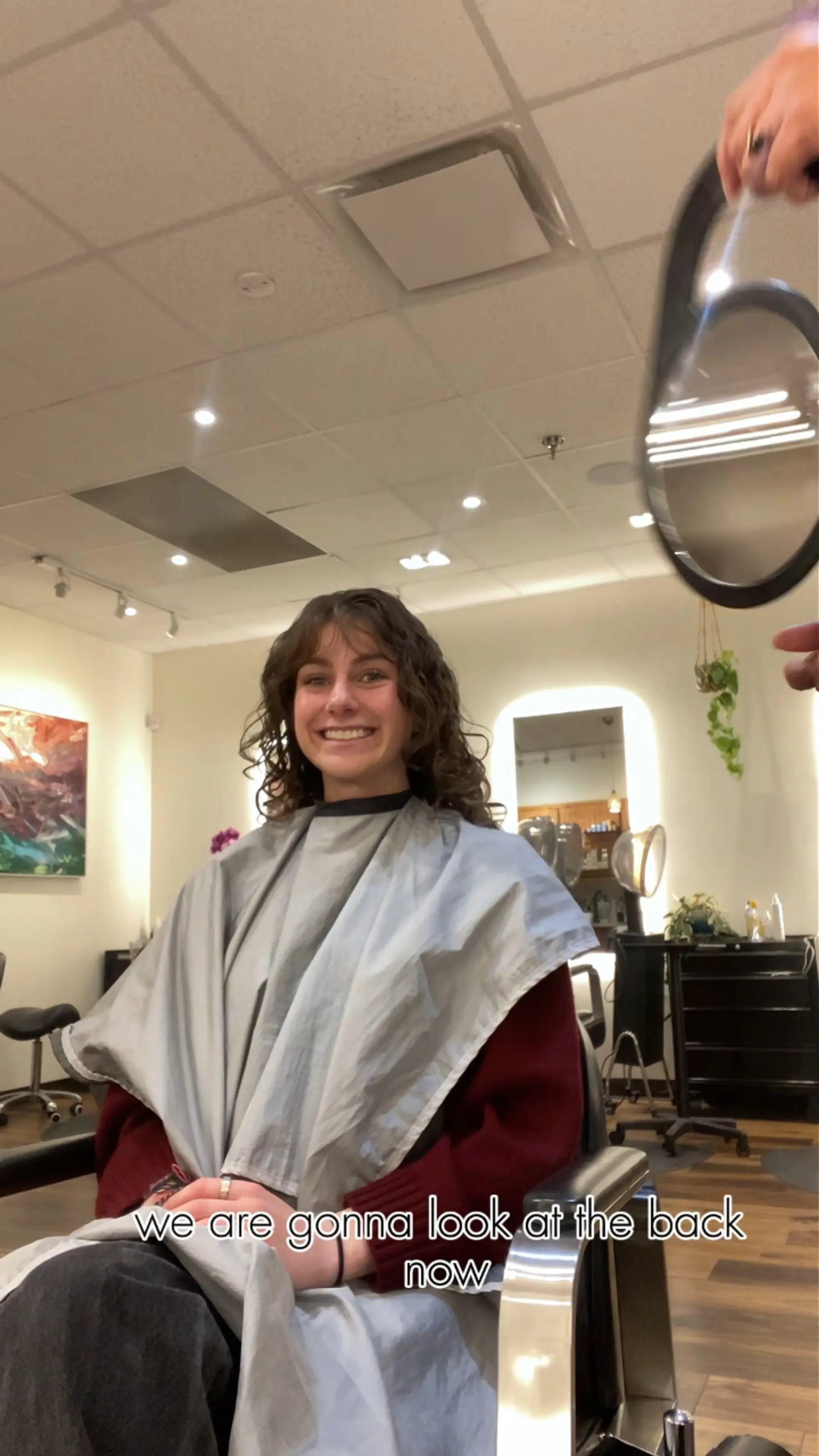 Medium-length naturally curly hair cut with rounded layers and soft textured curly bangs. 1