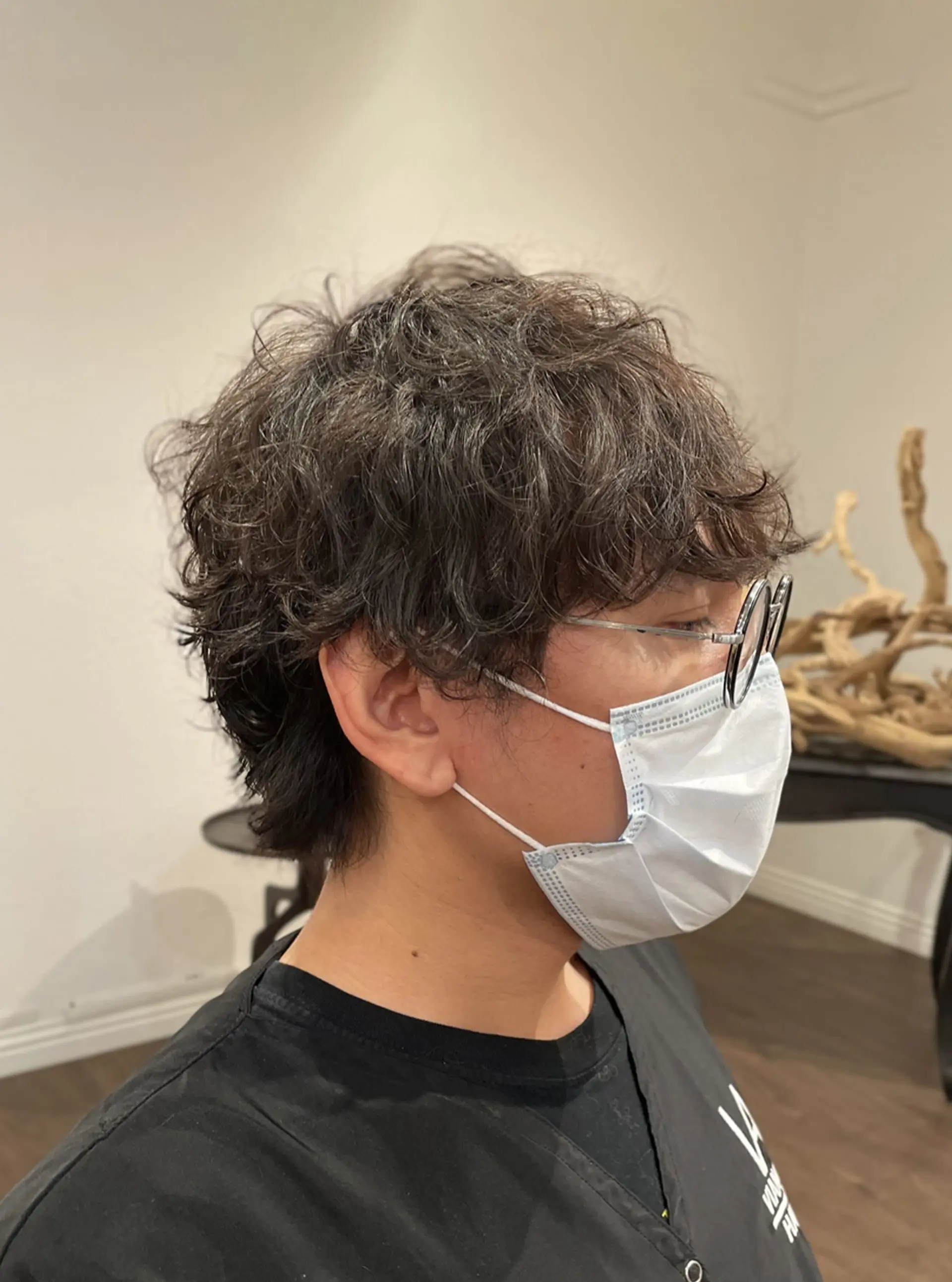 A textured men's short haircut featuring soft, natural perm waves that create gentle volume and movement. 1