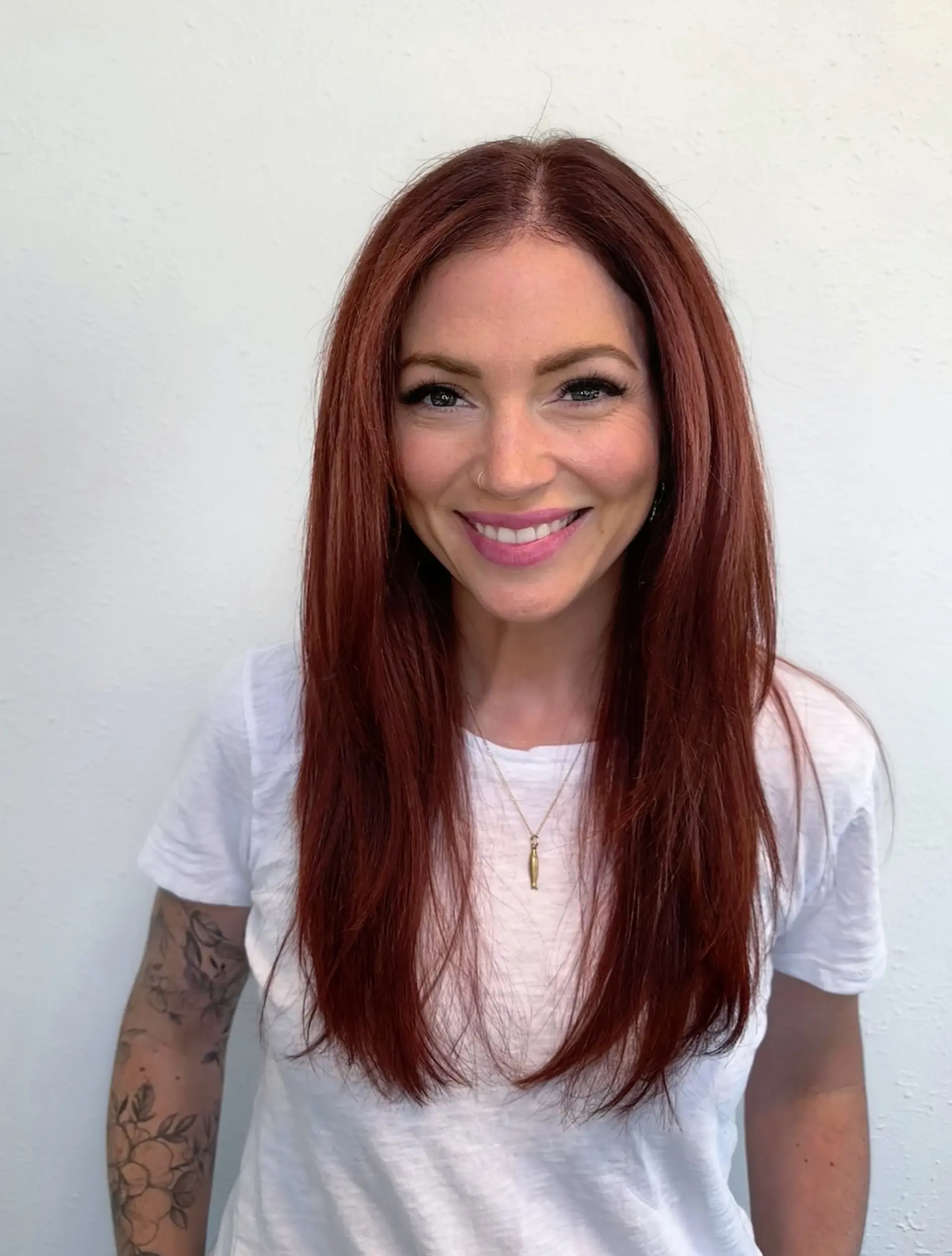 A rich, vibrant all-over auburn red hair color styled smooth and straight with long face-framing layers and a center part. 1