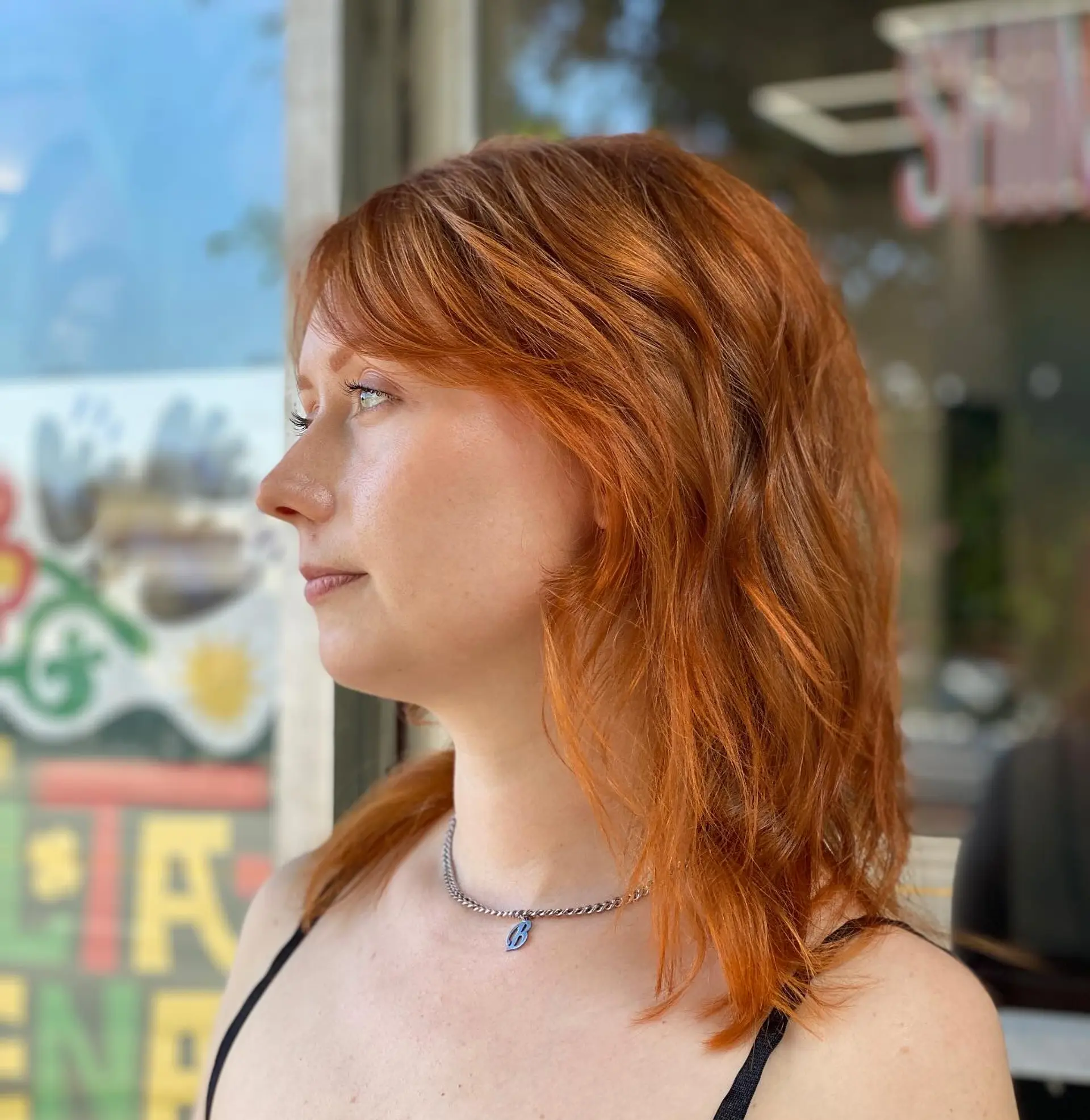 A textured medium-length shaggy haircut featuring soft, face-framing layers and wispy bangs in a rich copper tone. 1