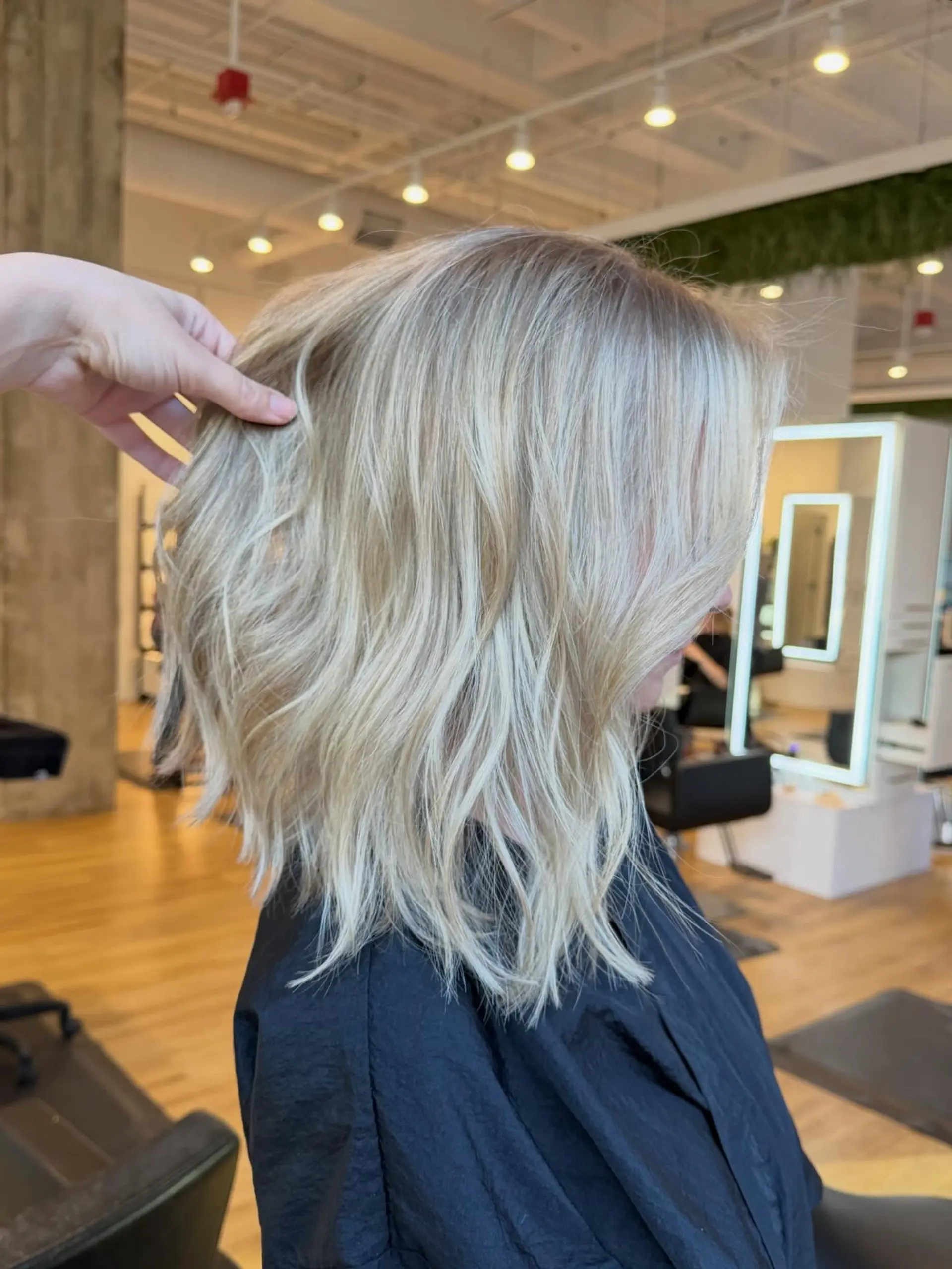 A textured shoulder-length lob styled with loose waves and bright blonde highlights. 1