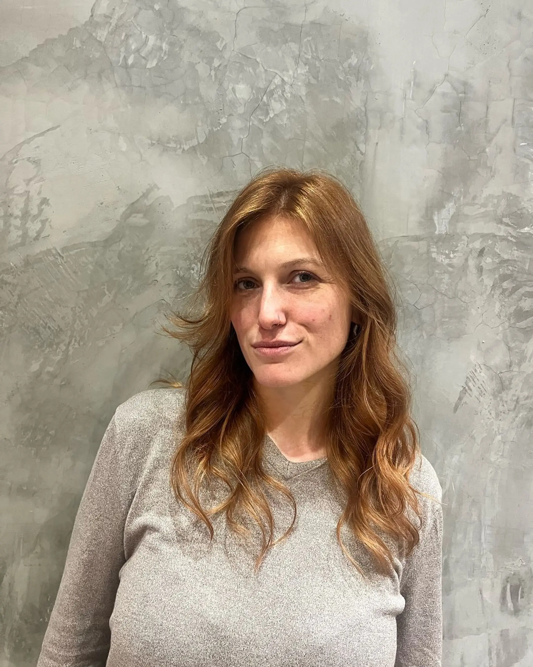 Soft, medium-length wavy curls in a golden brown color with honey highlights, featuring natural layers and face-framing waves.