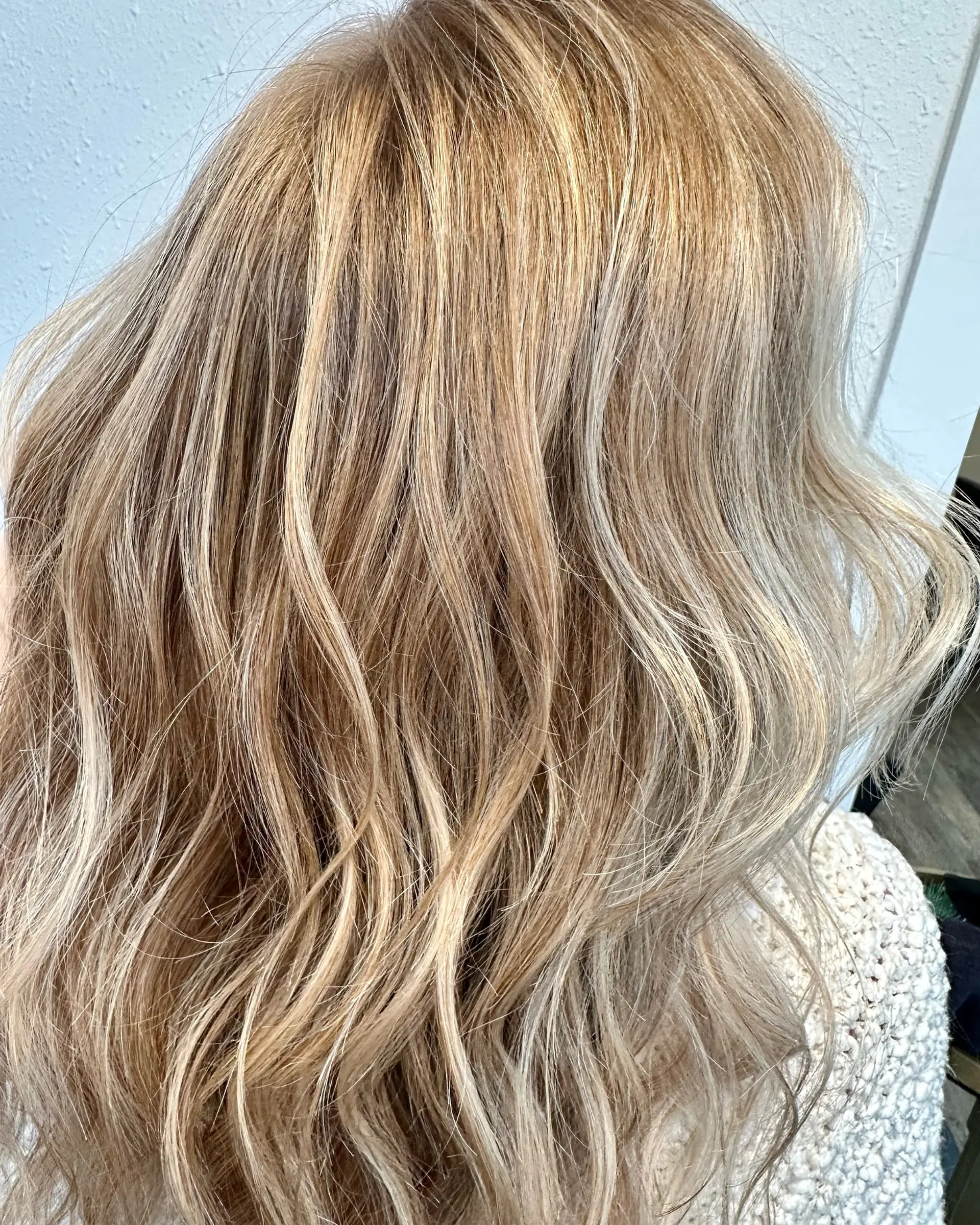 Dimensional, multi-toned blonde balayage with hand-painted highlights styled into loose, flowing waves. 1