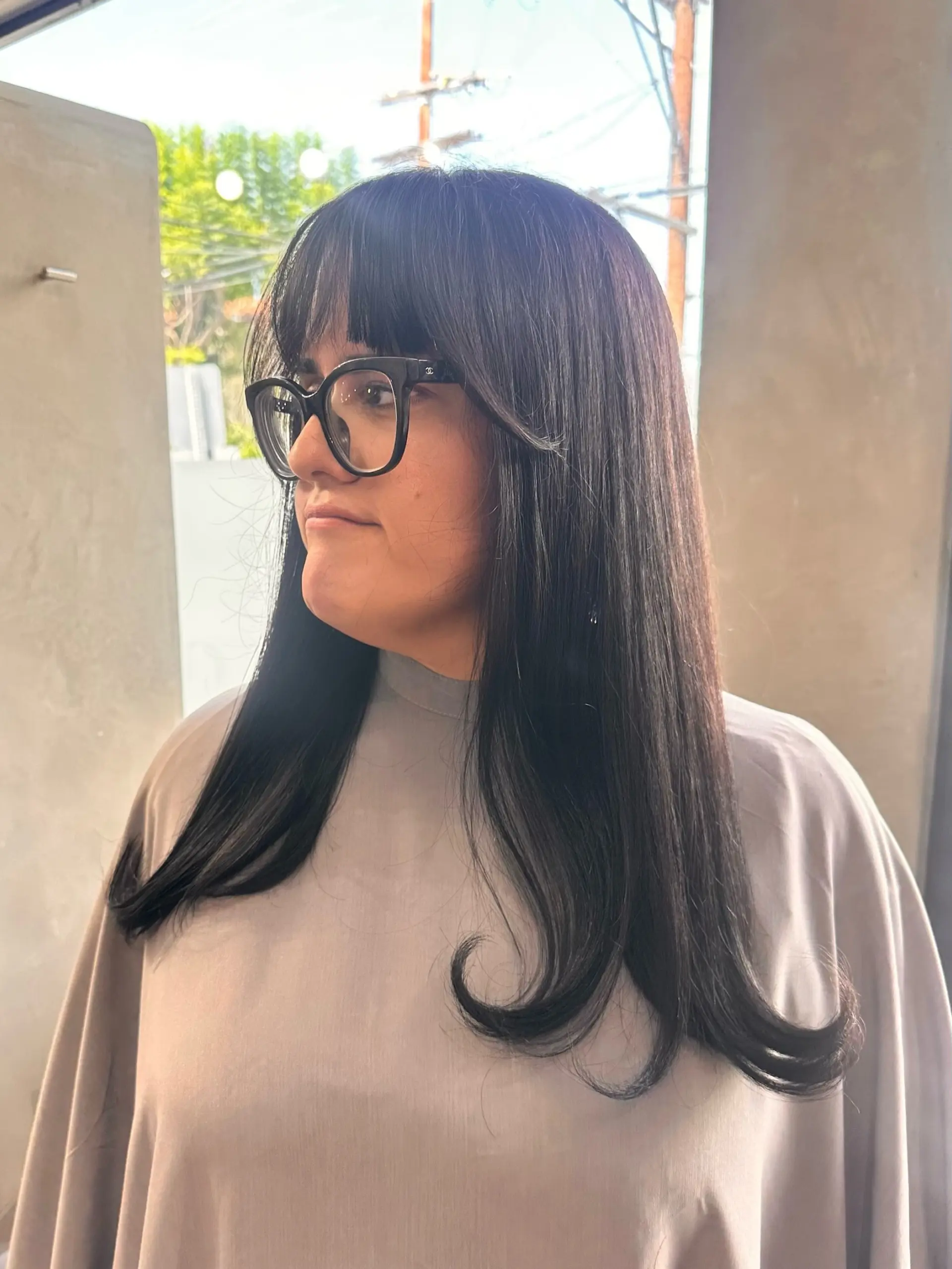 Long sleek dark hair featuring blunt eye-grazing bangs, subtle face-framing layers, and upward-flipped curled ends. 1