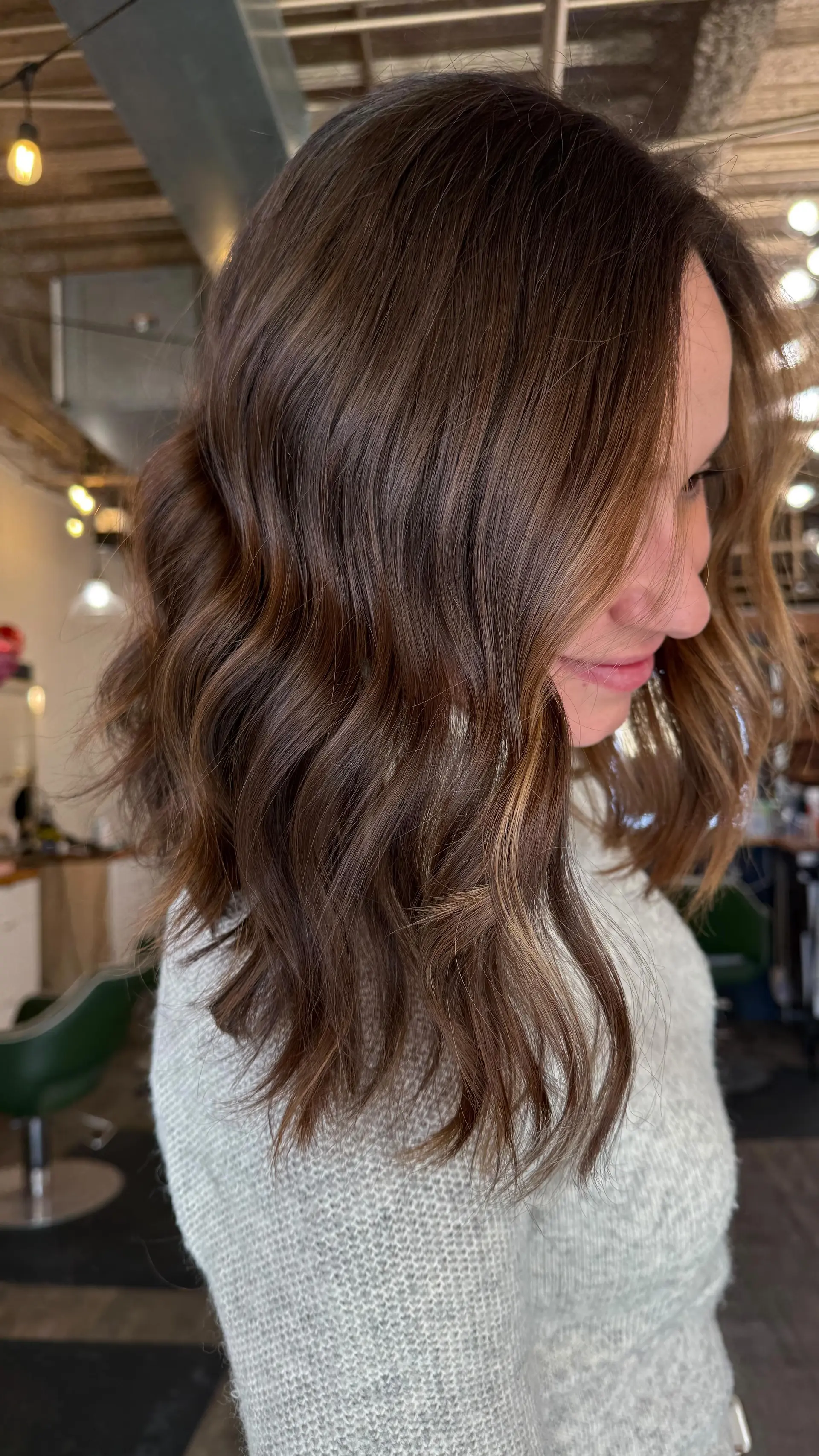 A medium-length textured lob styled into loose, effortless waves with subtle caramel balayage highlights. 1