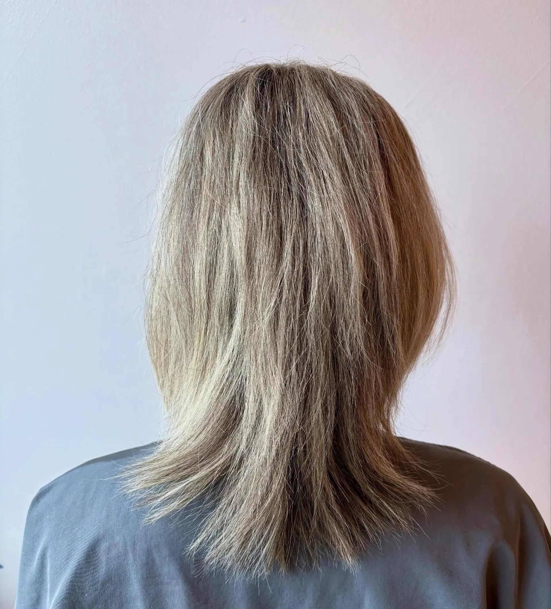 Medium-length light ash blonde hair featuring heavily textured, layered ends with a soft outward flick. 1