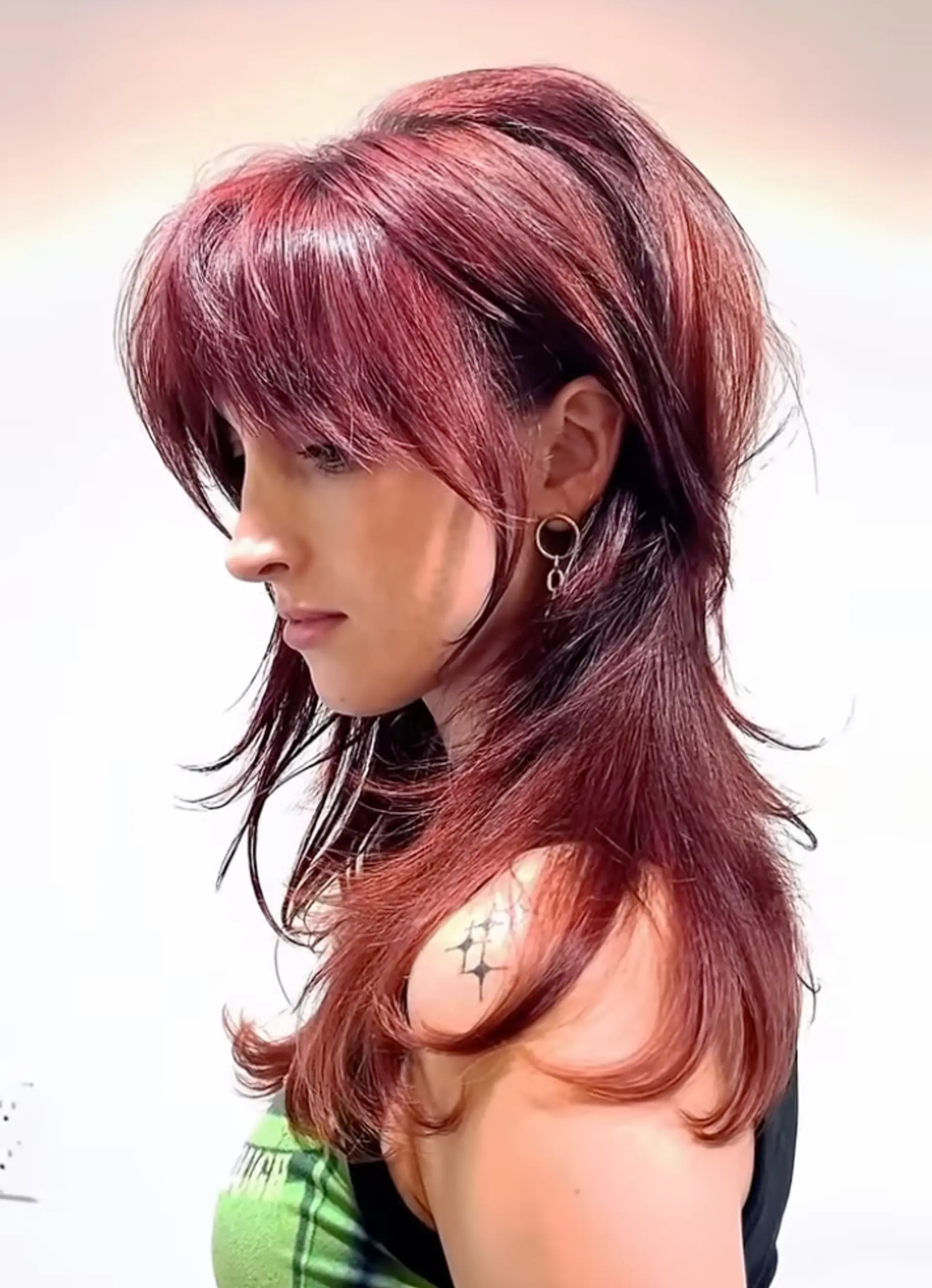 Long wavy hairstyle with dark red and crimson colors. Features voluminous layers, feathered fringe, and textured ends. 1